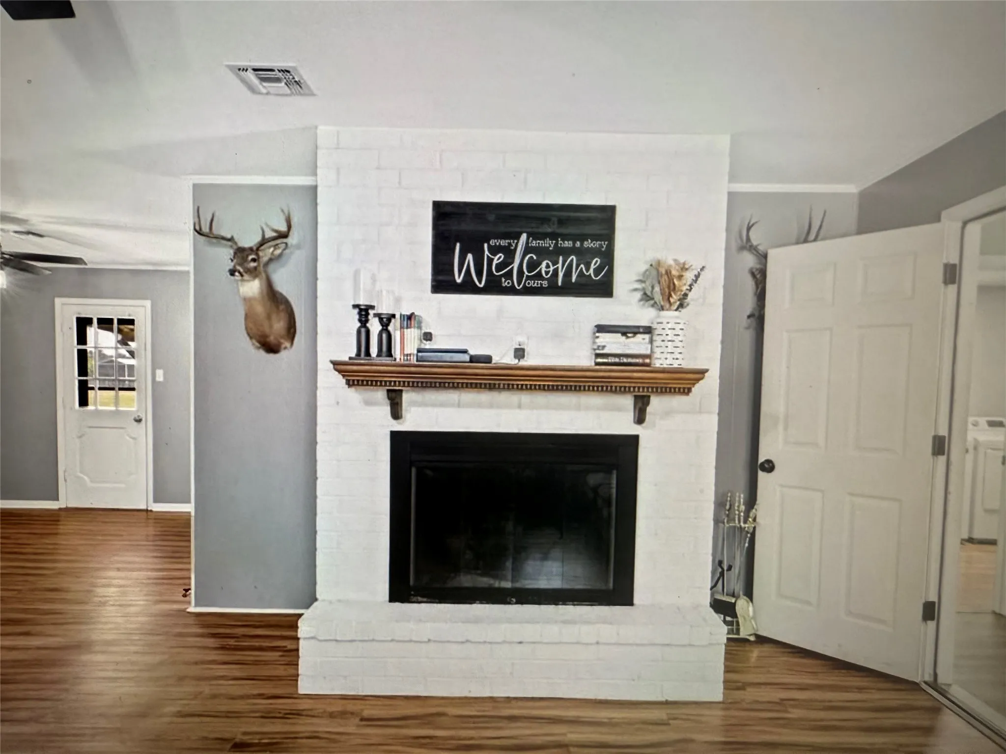 Detailed view of a fireplace, wood finished floors, washer / dryer, crown molding, and ceiling fan
