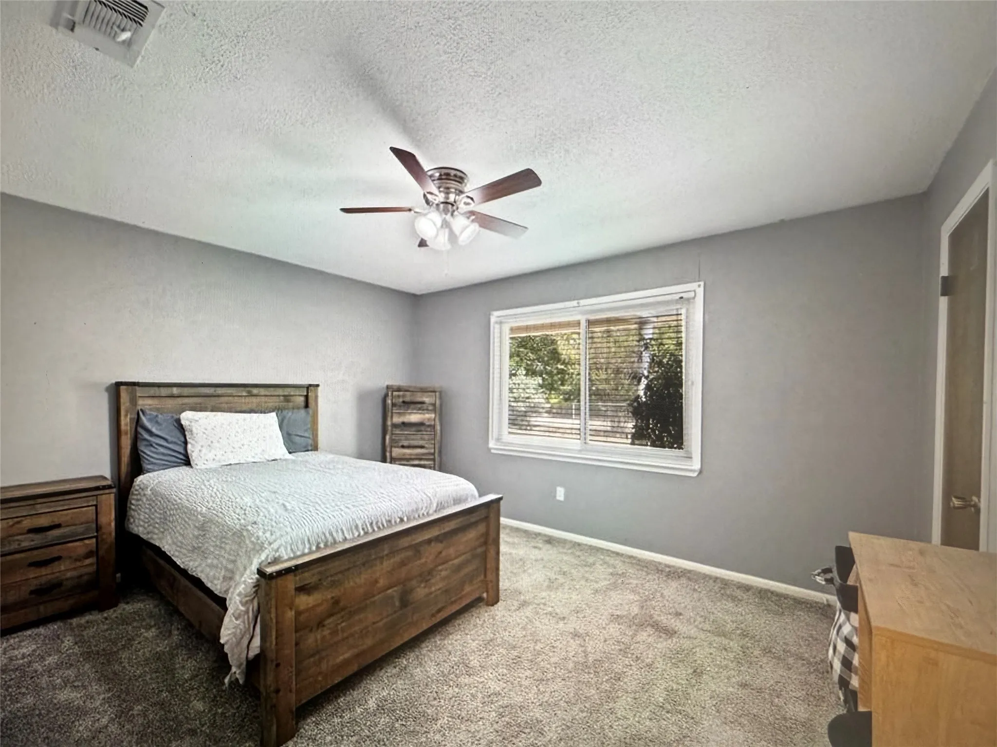 Carpeted bedroom with a textured ceiling and a ceiling fan