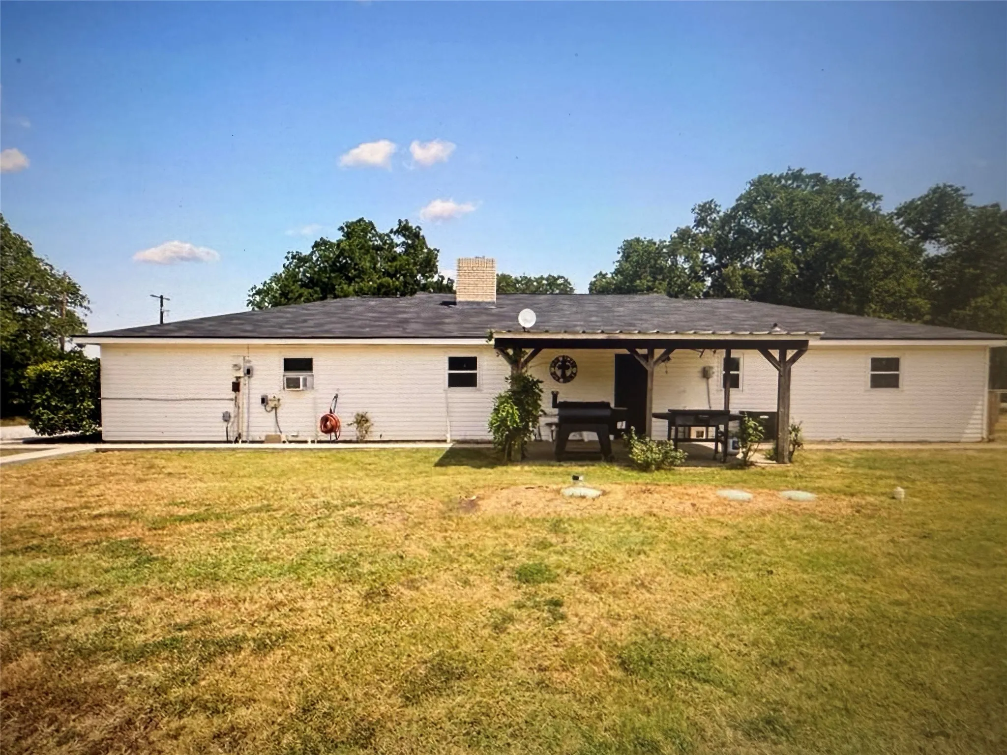 Back of house with a chimney, a lawn, and a patio area