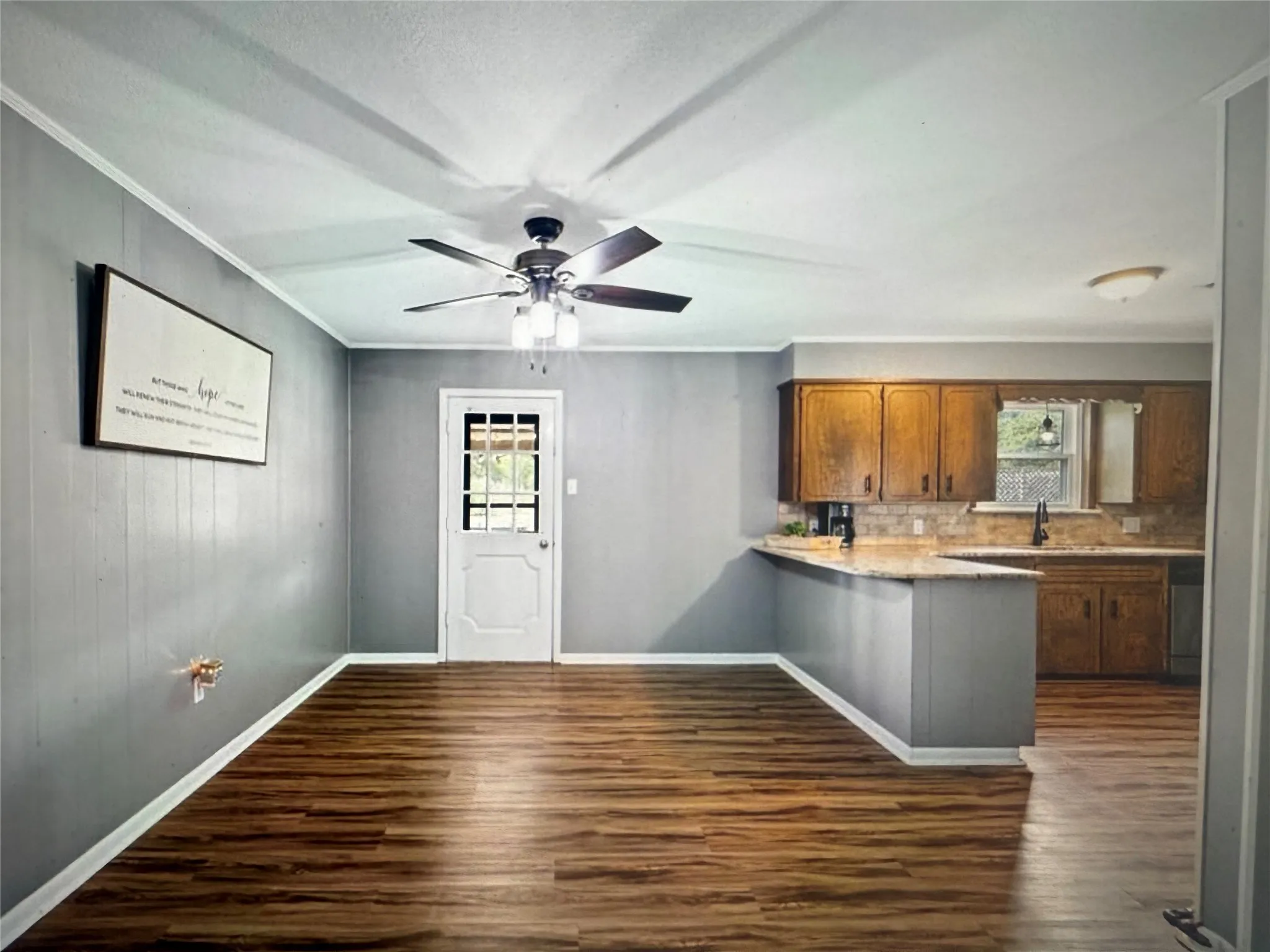 Kitchen with light countertops, dark wood finished floors, ornamental molding, a peninsula, and brown cabinets