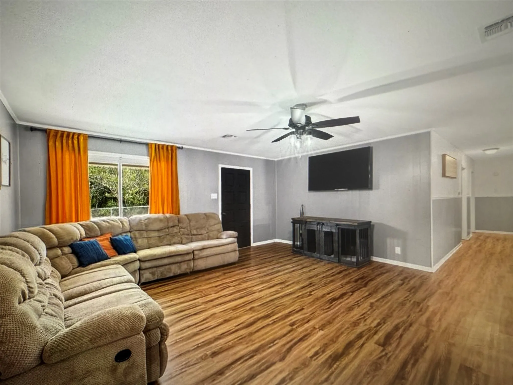 Living room with wood finished floors, ceiling fan, and ornamental molding