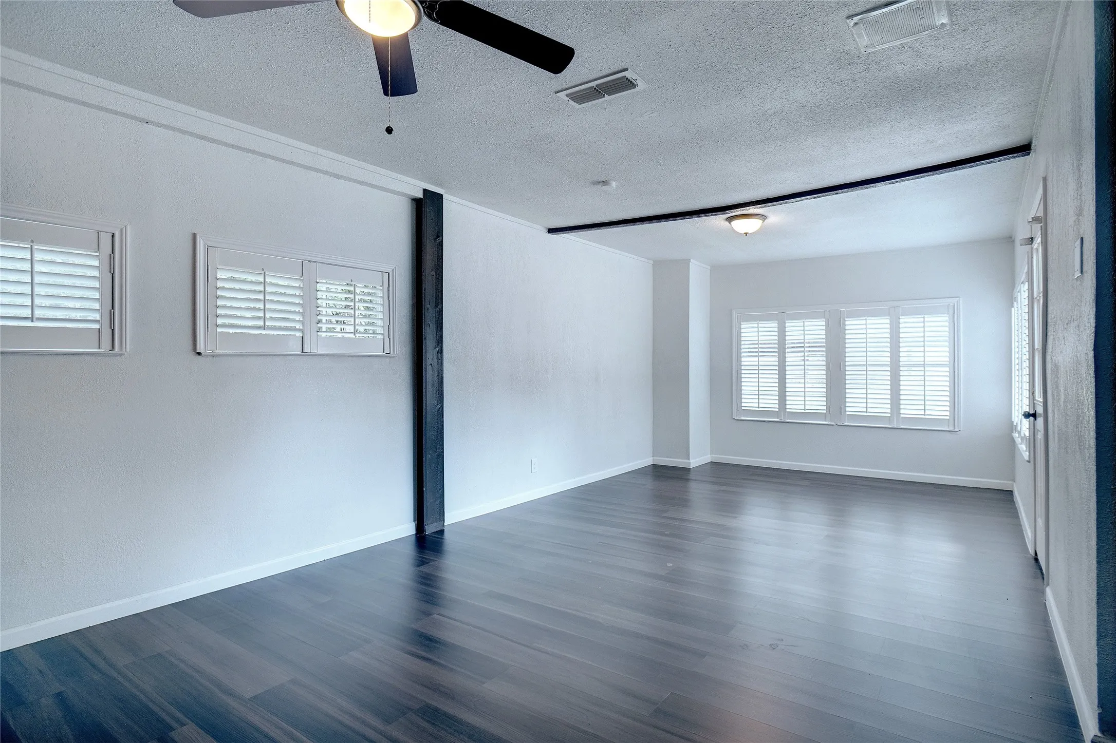 Spare room with a textured ceiling, dark wood-style floors, and a ceiling fan