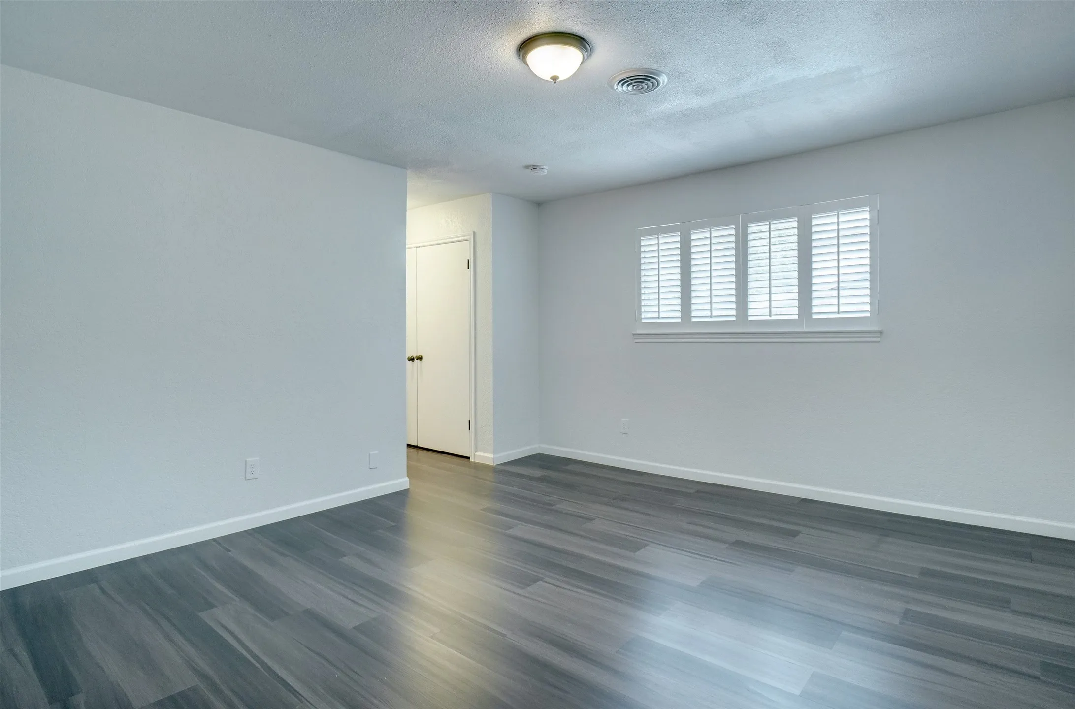 Spare room with dark wood-type flooring and a textured ceiling