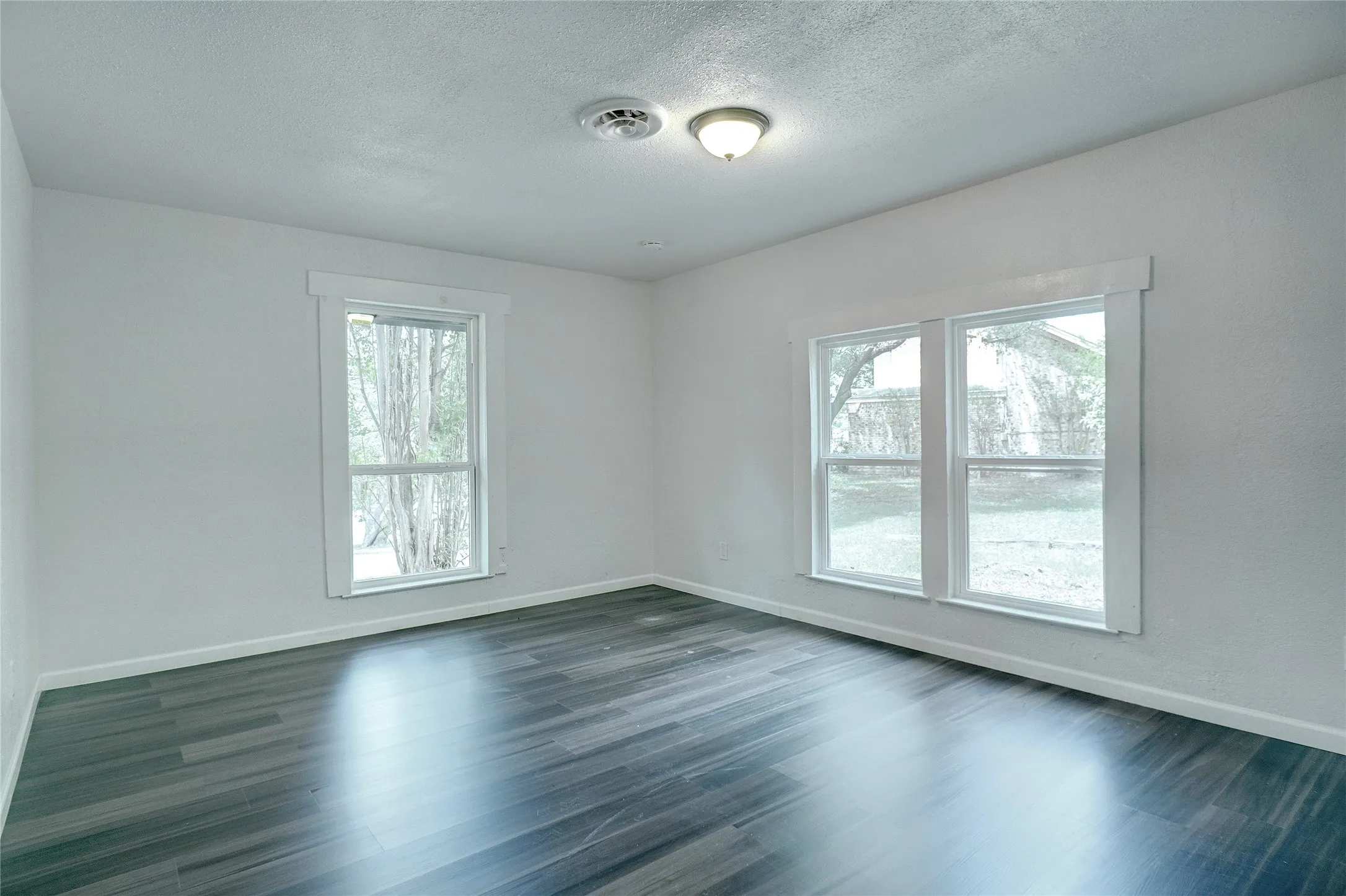 Spare room with a textured ceiling and dark wood-style floors