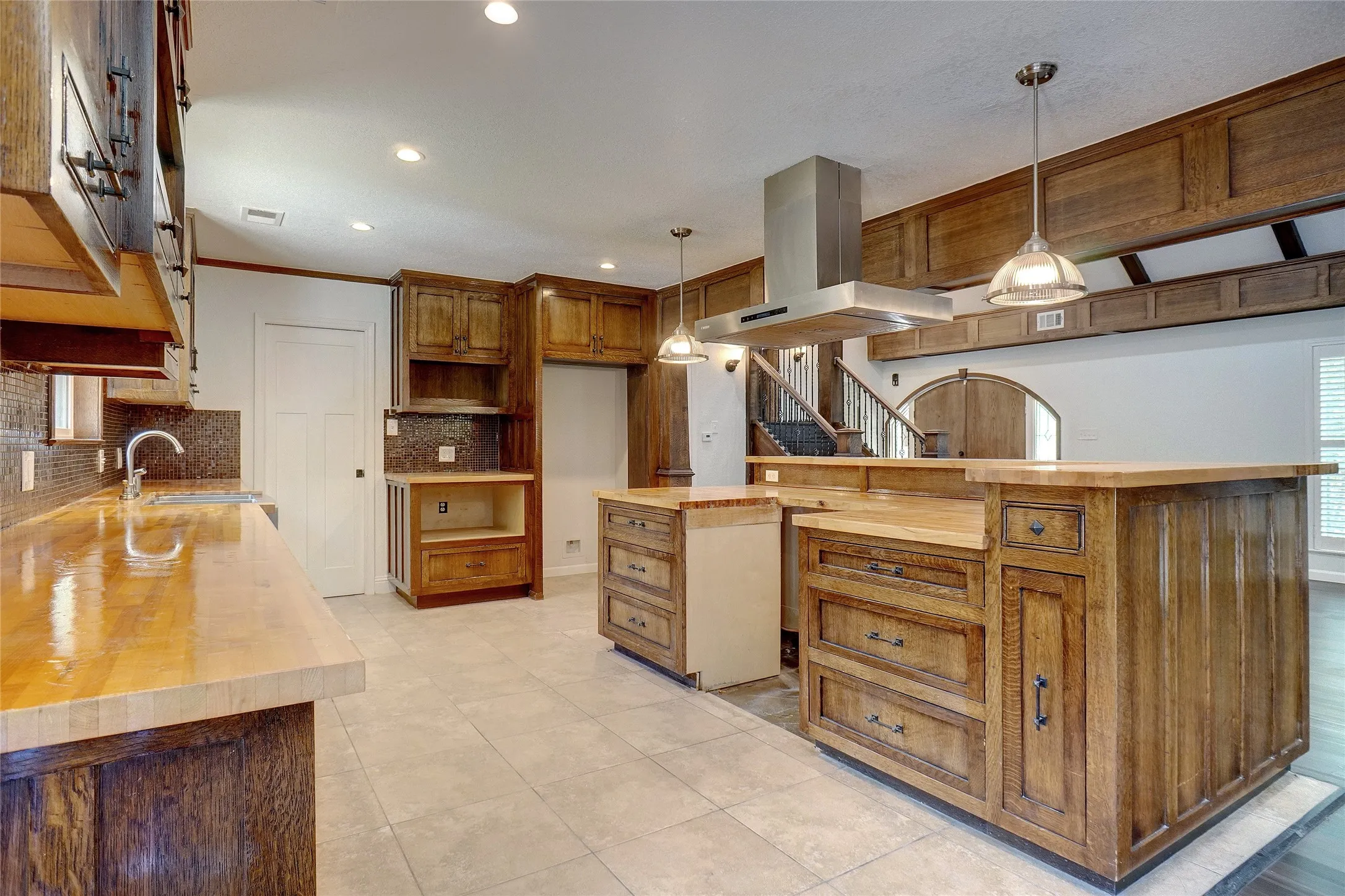 Kitchen featuring wood counters, wall chimney range hood, recessed lighting, tasteful backsplash, and ornamental molding