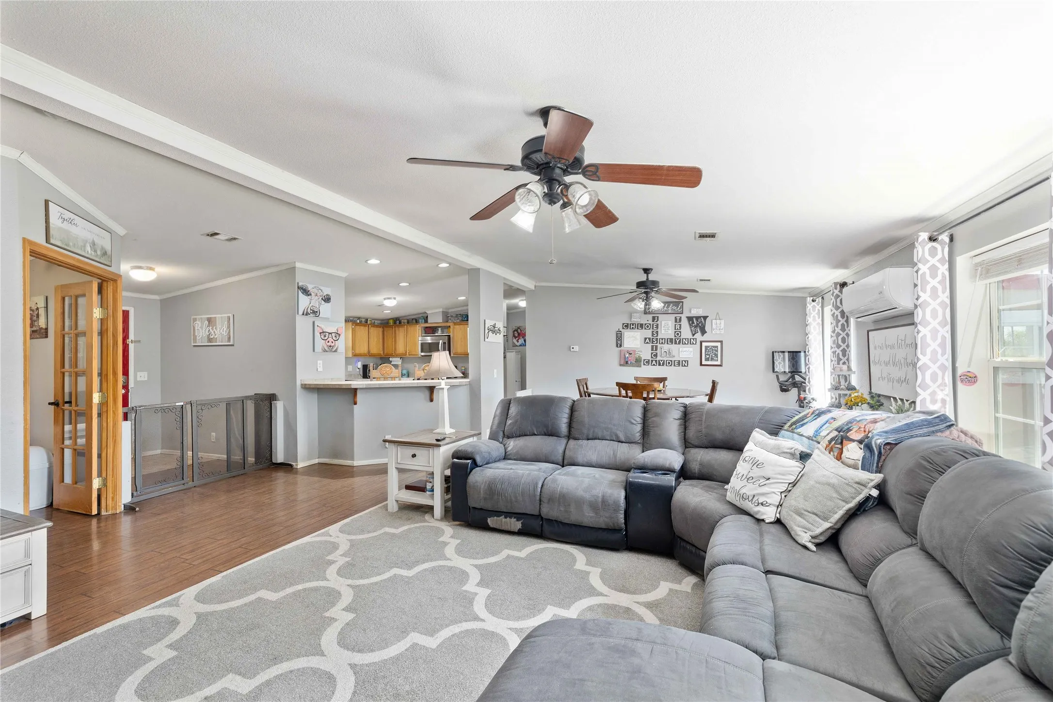 Living room featuring crown molding, wood finished floors, a wall mounted AC, recessed lighting, and a ceiling fan