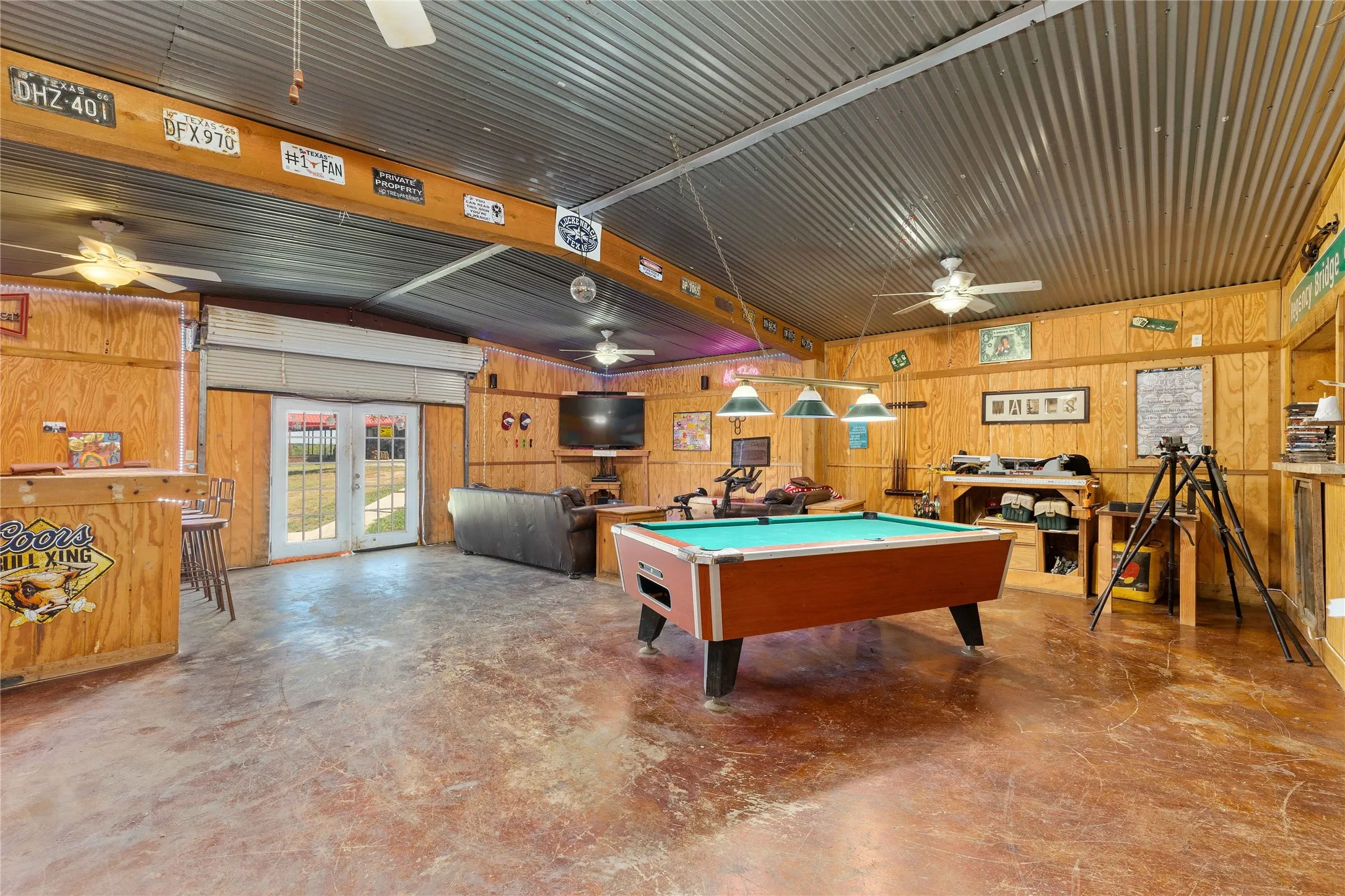 Rec room featuring billiards table, finished concrete floors, wood walls, and french doors