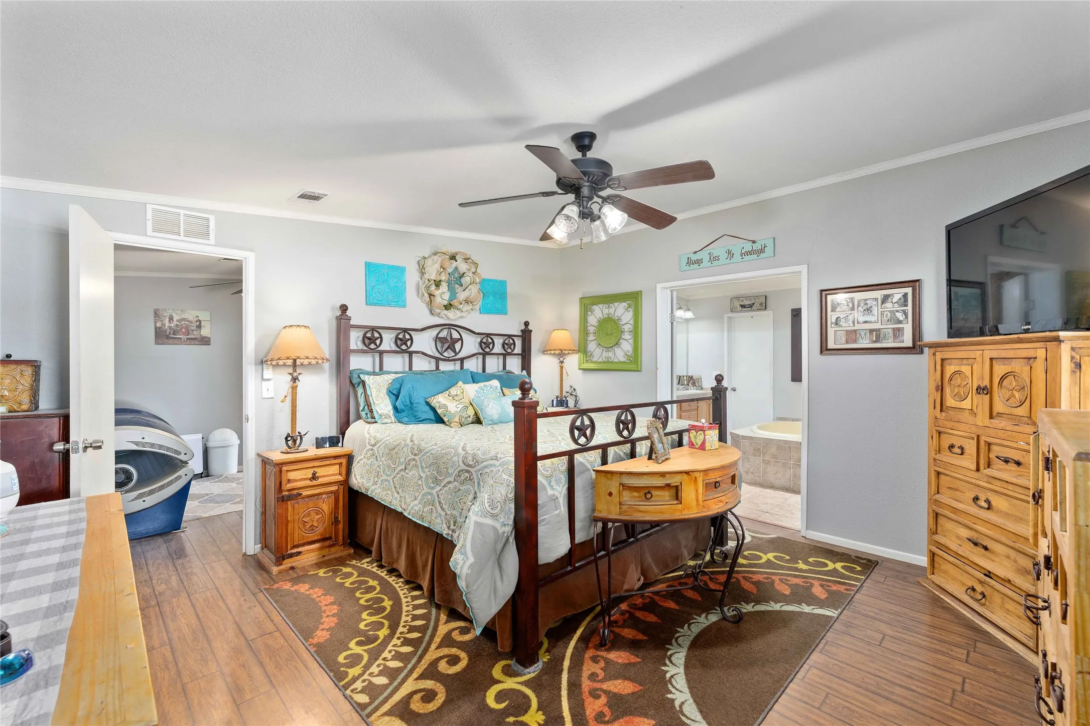 Bedroom featuring ornamental molding, dark wood-style floors, ensuite bath, and ceiling fan