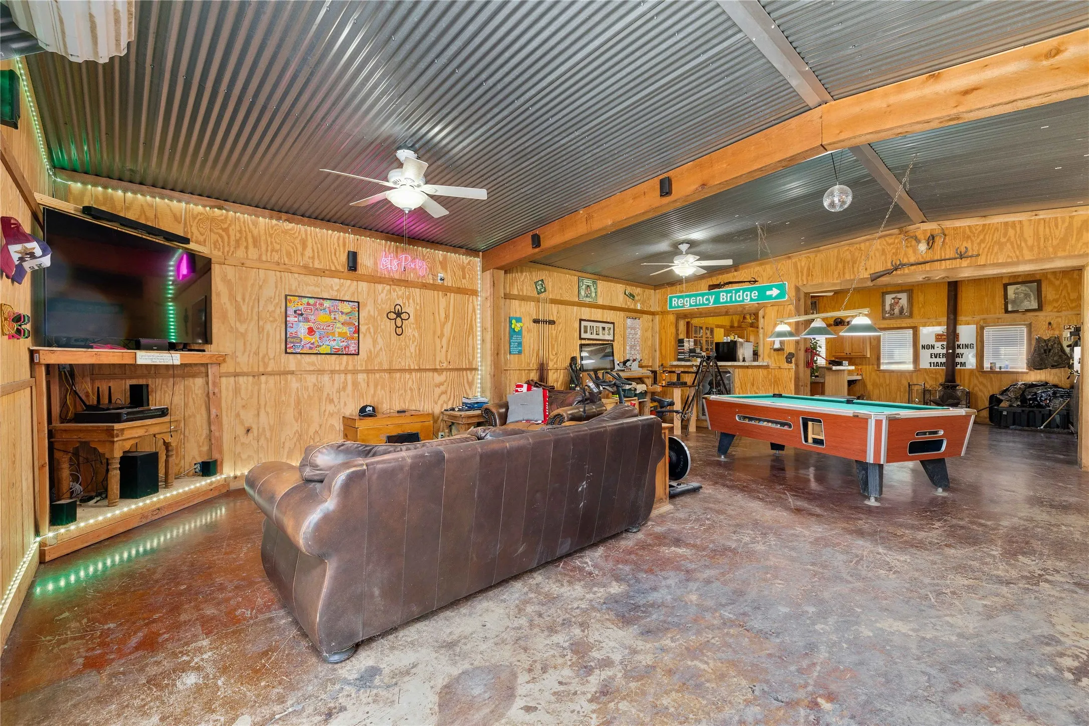 Living area with wood walls, billiards, beam ceiling, and concrete floors