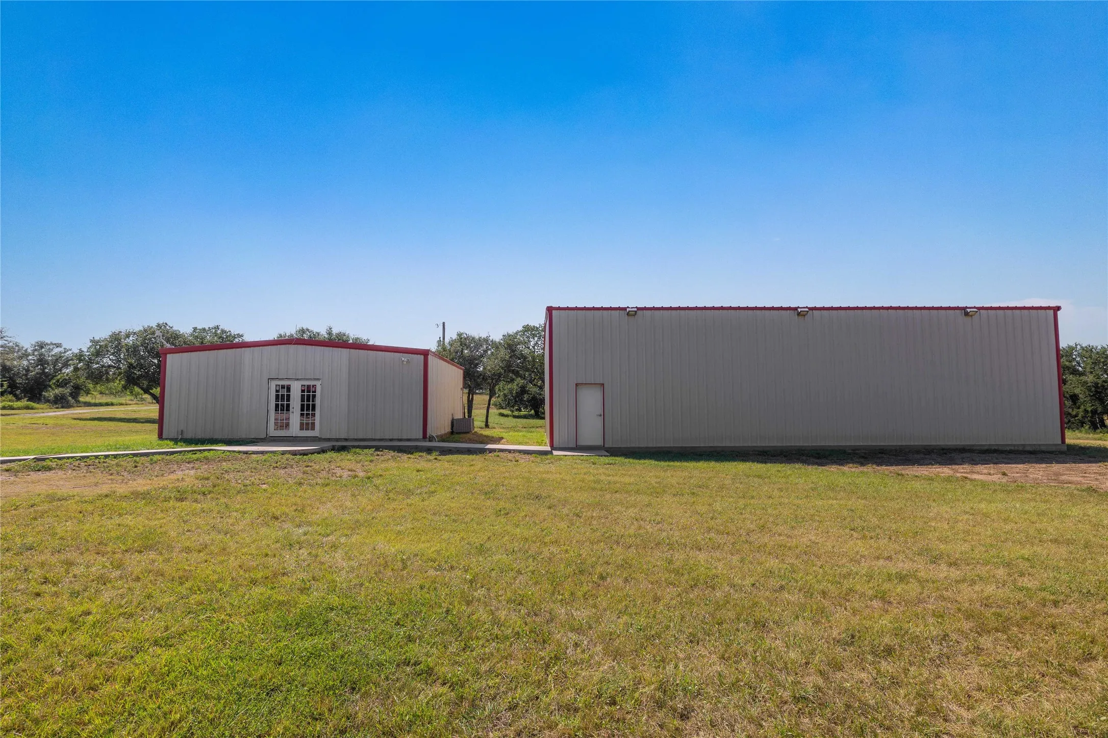 View of green lawn with a pole building and an outbuilding