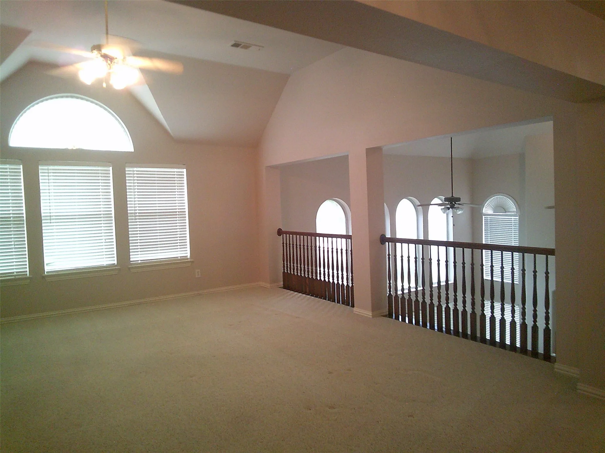 Unfurnished room with a ceiling fan, vaulted ceiling, carpet, and plenty of natural light