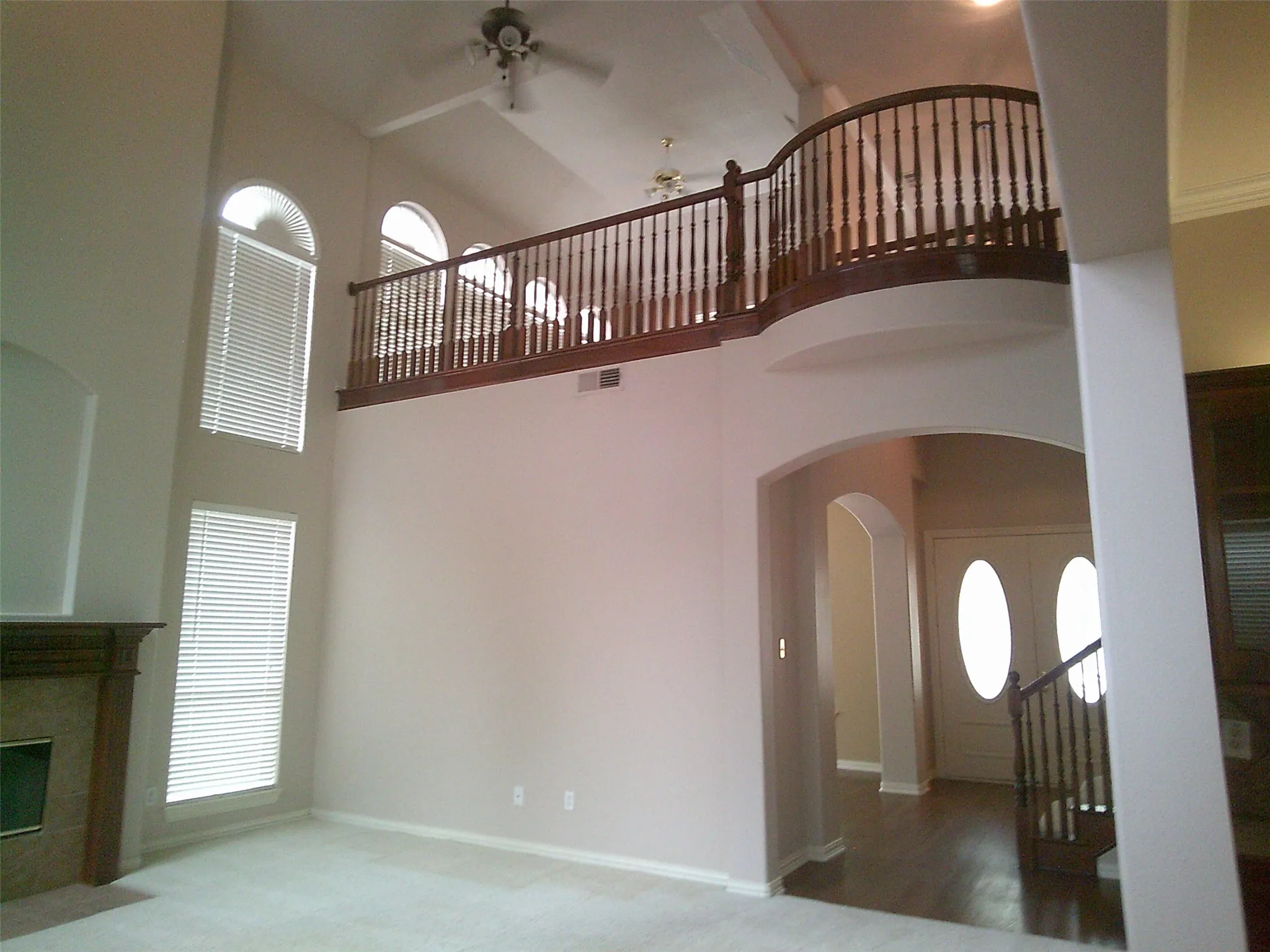 Unfurnished living room with a high ceiling, ceiling fan, arched walkways, carpet floors, and a tile fireplace