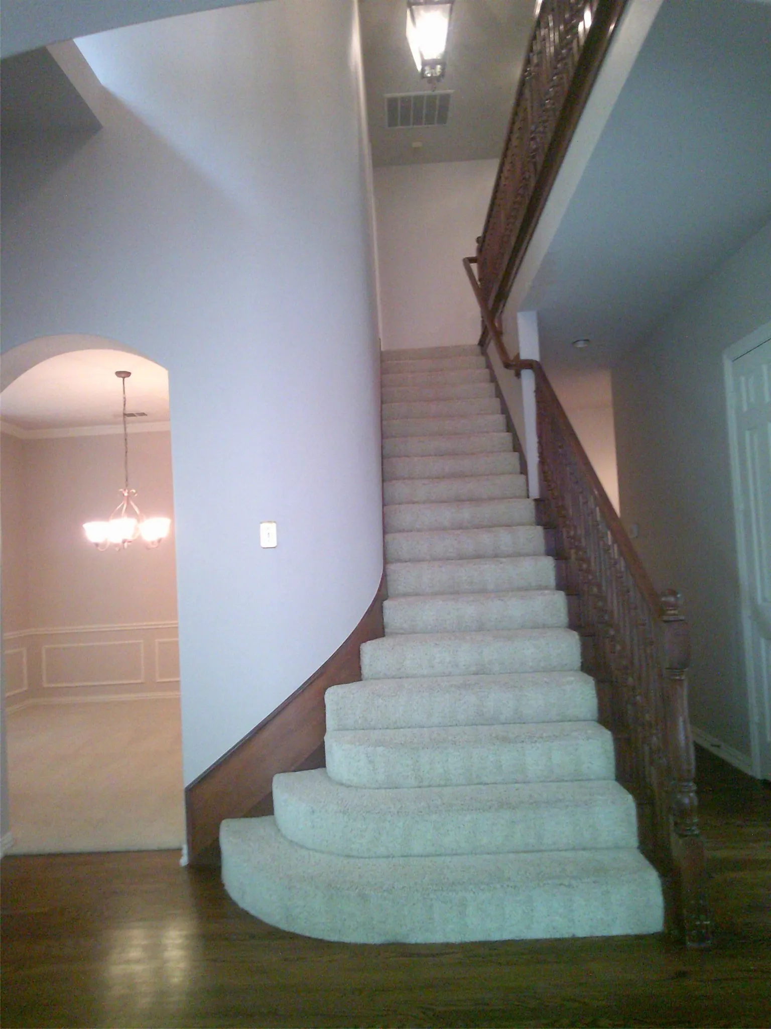 Staircase with wood finished floors, arched walkways, a chandelier, and crown molding