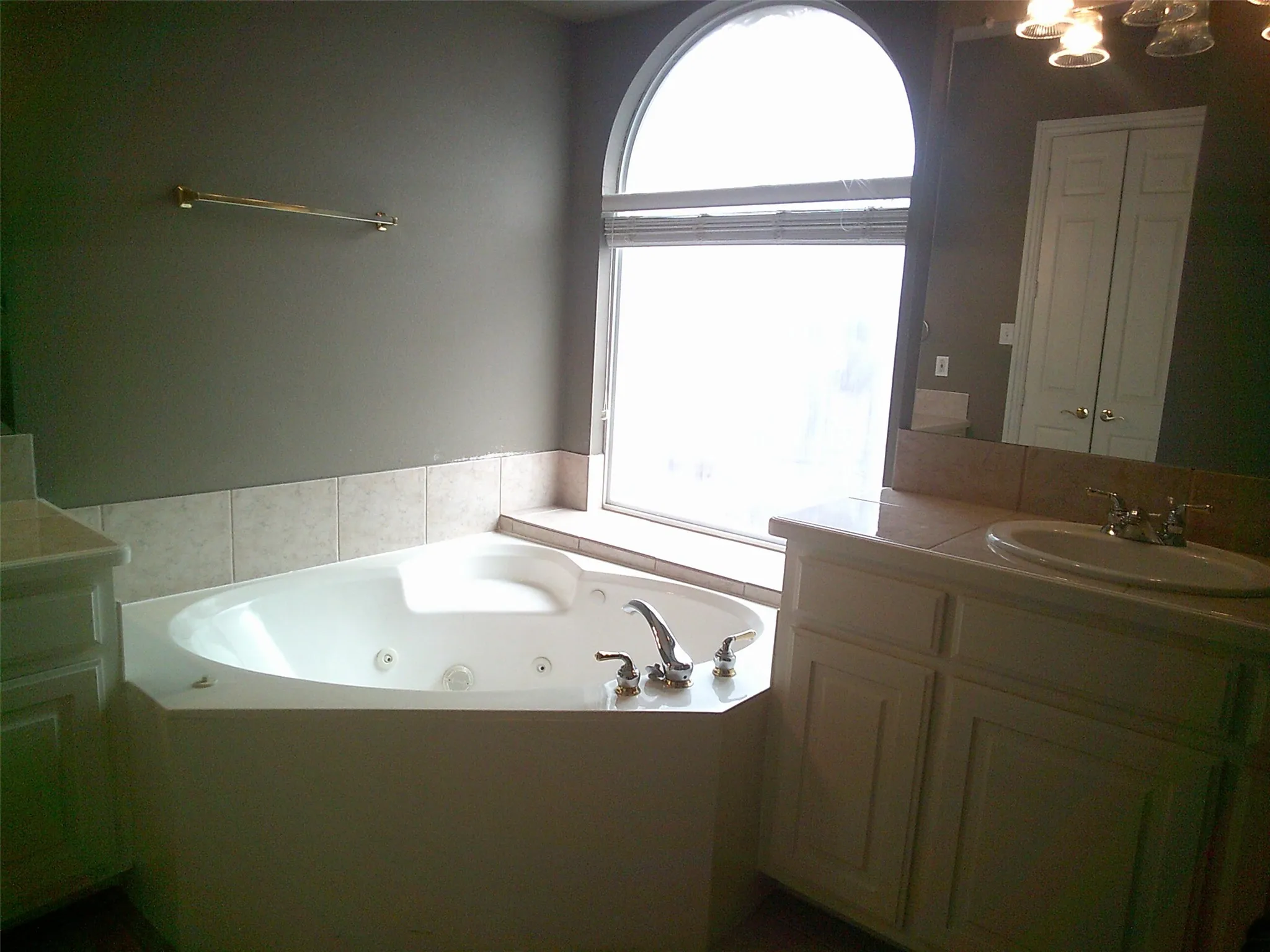 Bathroom with vanity, a jetted tub, and a chandelier