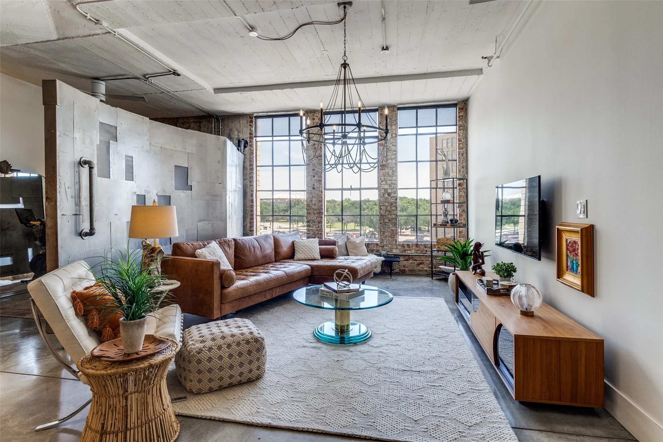 Living room featuring a chandelier and finished concrete flooring. Unique metal divider creates additional versatile space