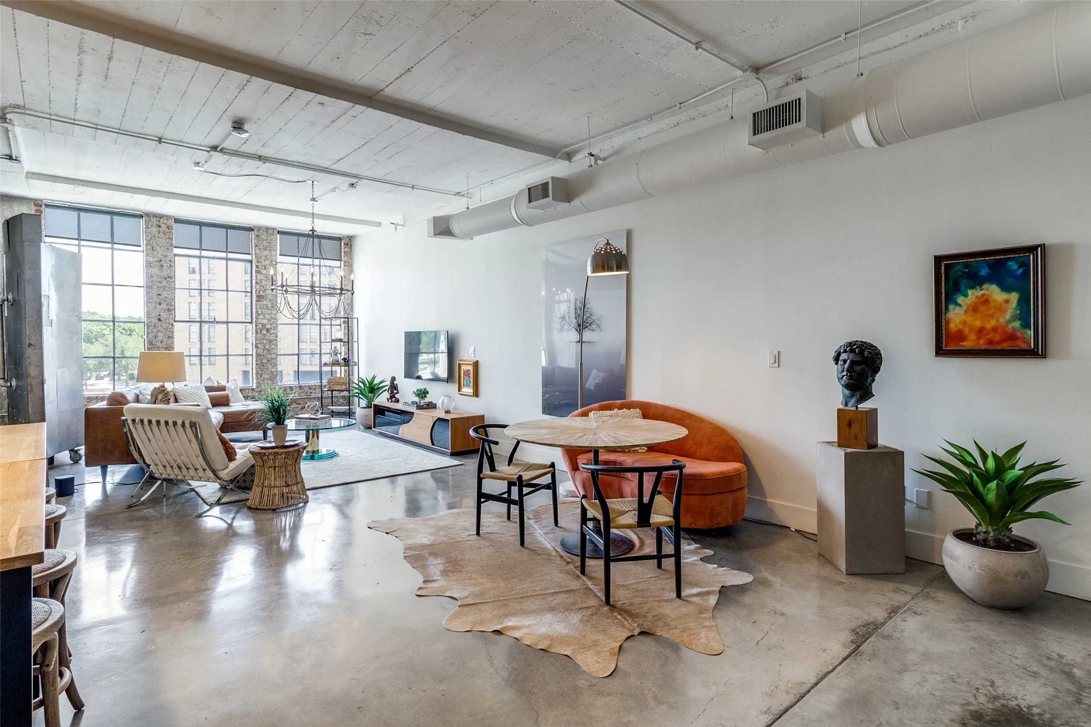 Living space featuring finished concrete flooring, track lighting, baseboards, floor to ceiling windows and sitting area