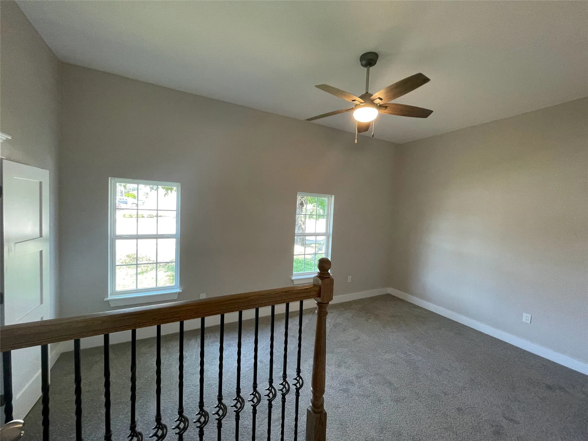 Carpeted empty room featuring baseboards and a ceiling fan