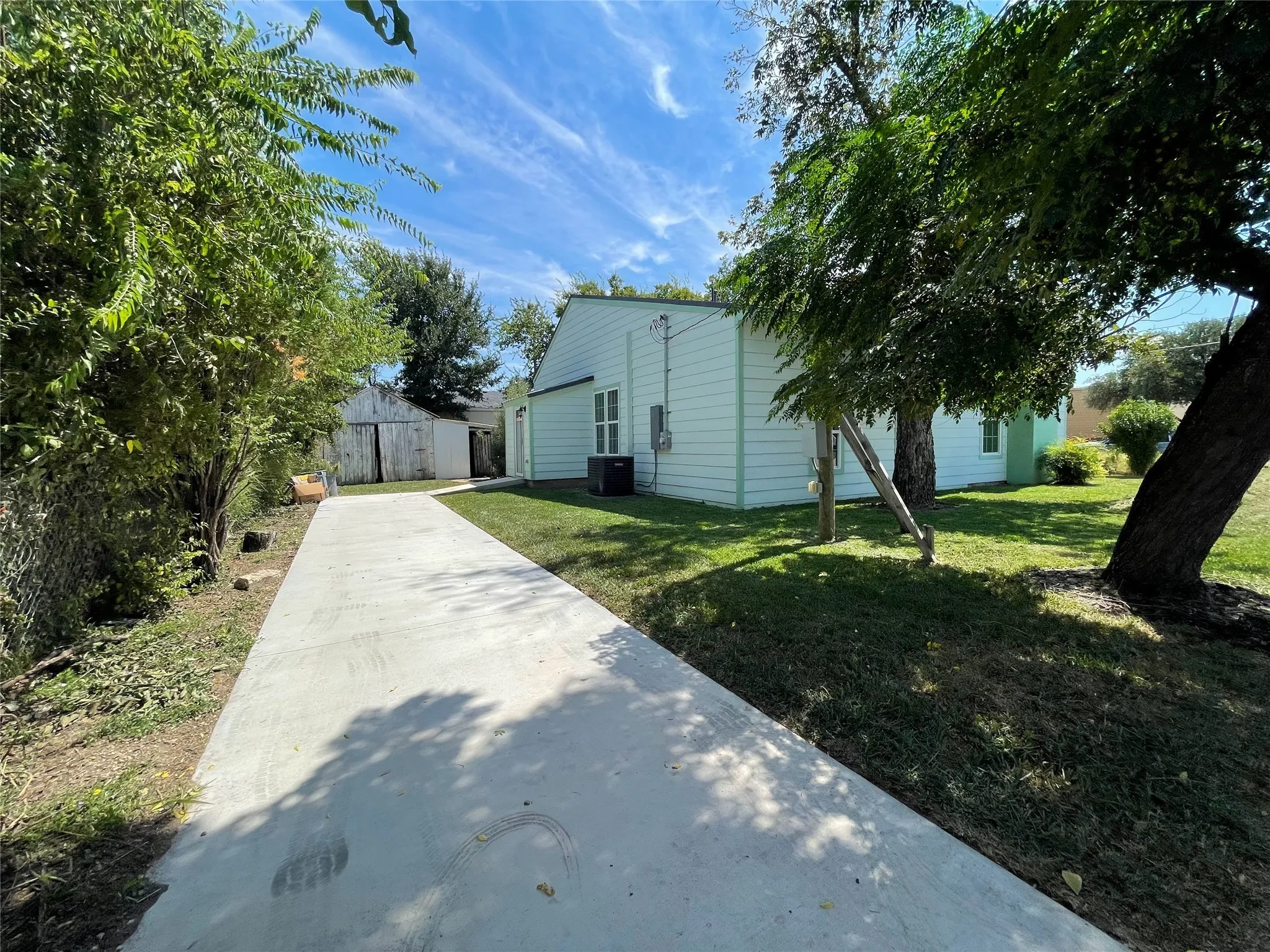 View of home's exterior featuring driveway, a yard, and an outbuilding