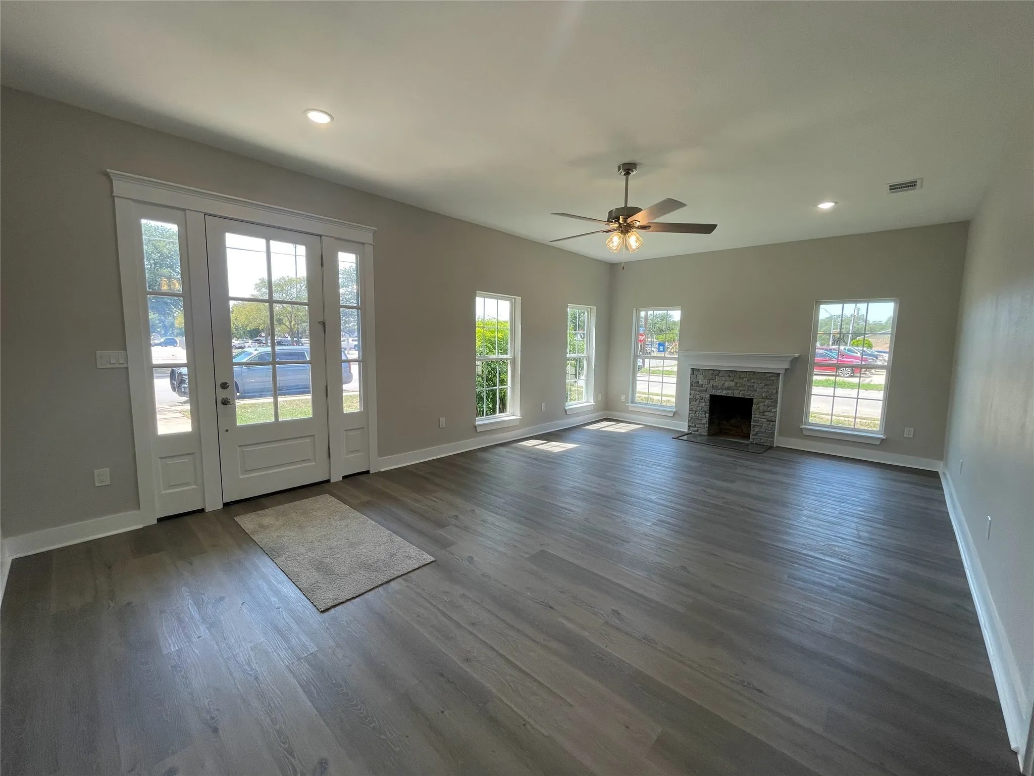 Unfurnished living room with recessed lighting, ceiling fan, dark wood finished floors, and a fireplace
