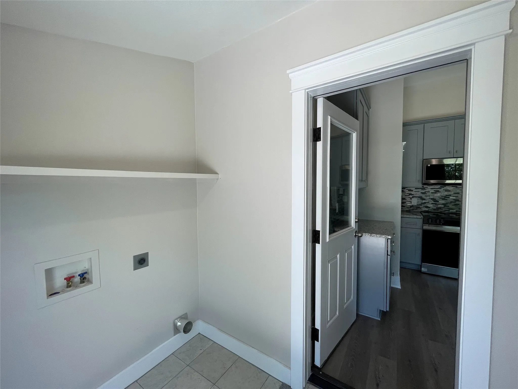 Washroom with hookup for an electric dryer, dark tile patterned floors, and washer hookup