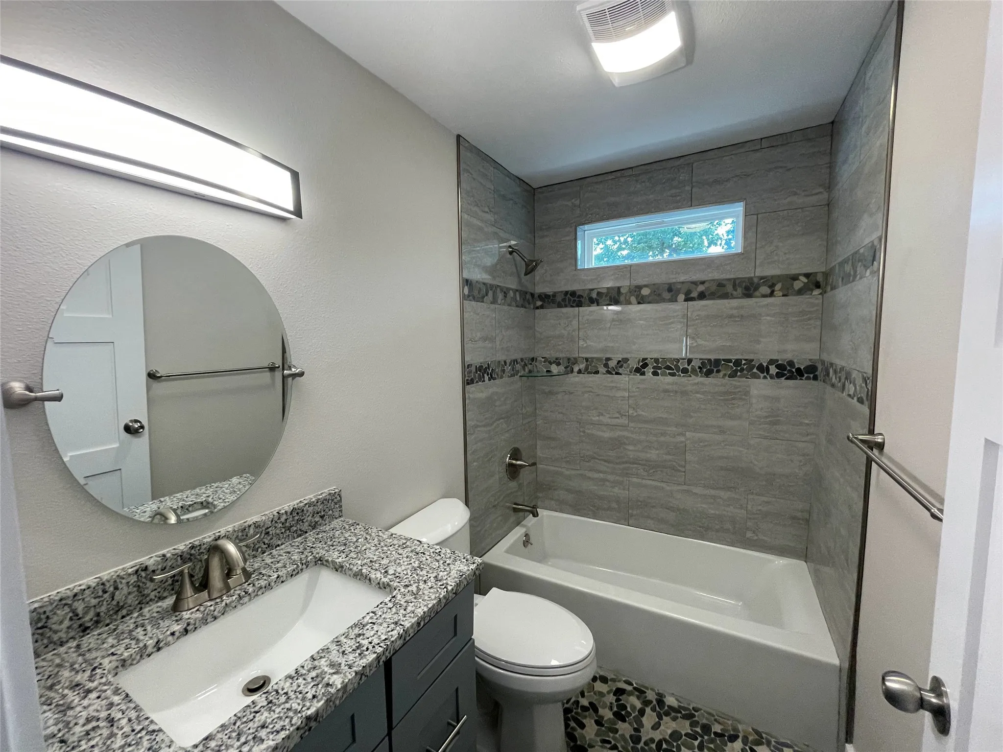Bathroom with bathtub / shower combination, vanity, and a textured wall