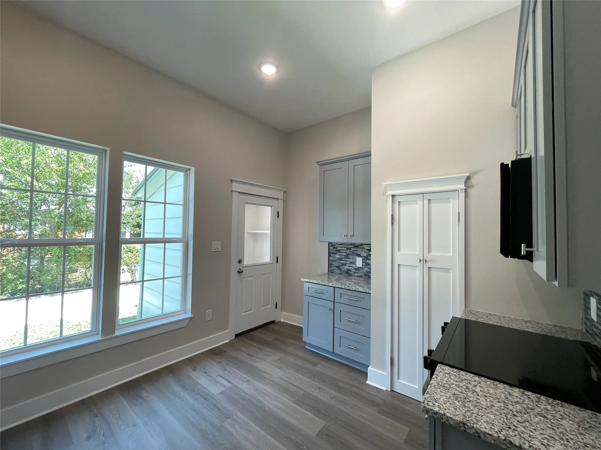 Kitchen featuring gray cabinetry, dark wood-style floors, light stone countertops, backsplash, and recessed lighting