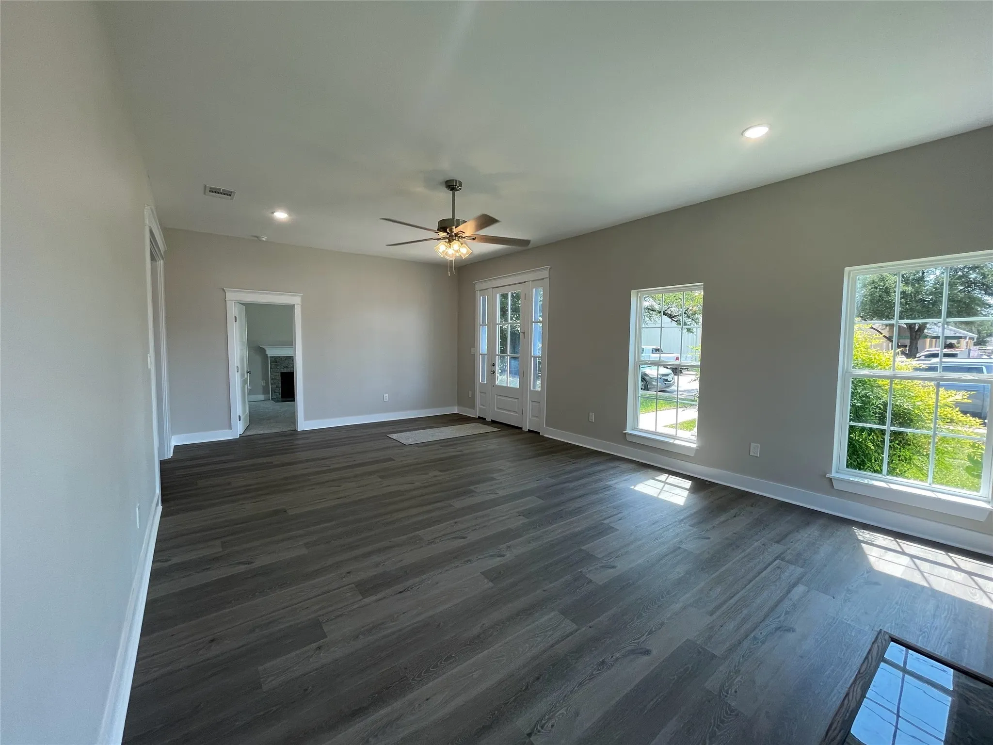 Unfurnished living room with dark wood finished floors, ceiling fan, a fireplace, and recessed lighting