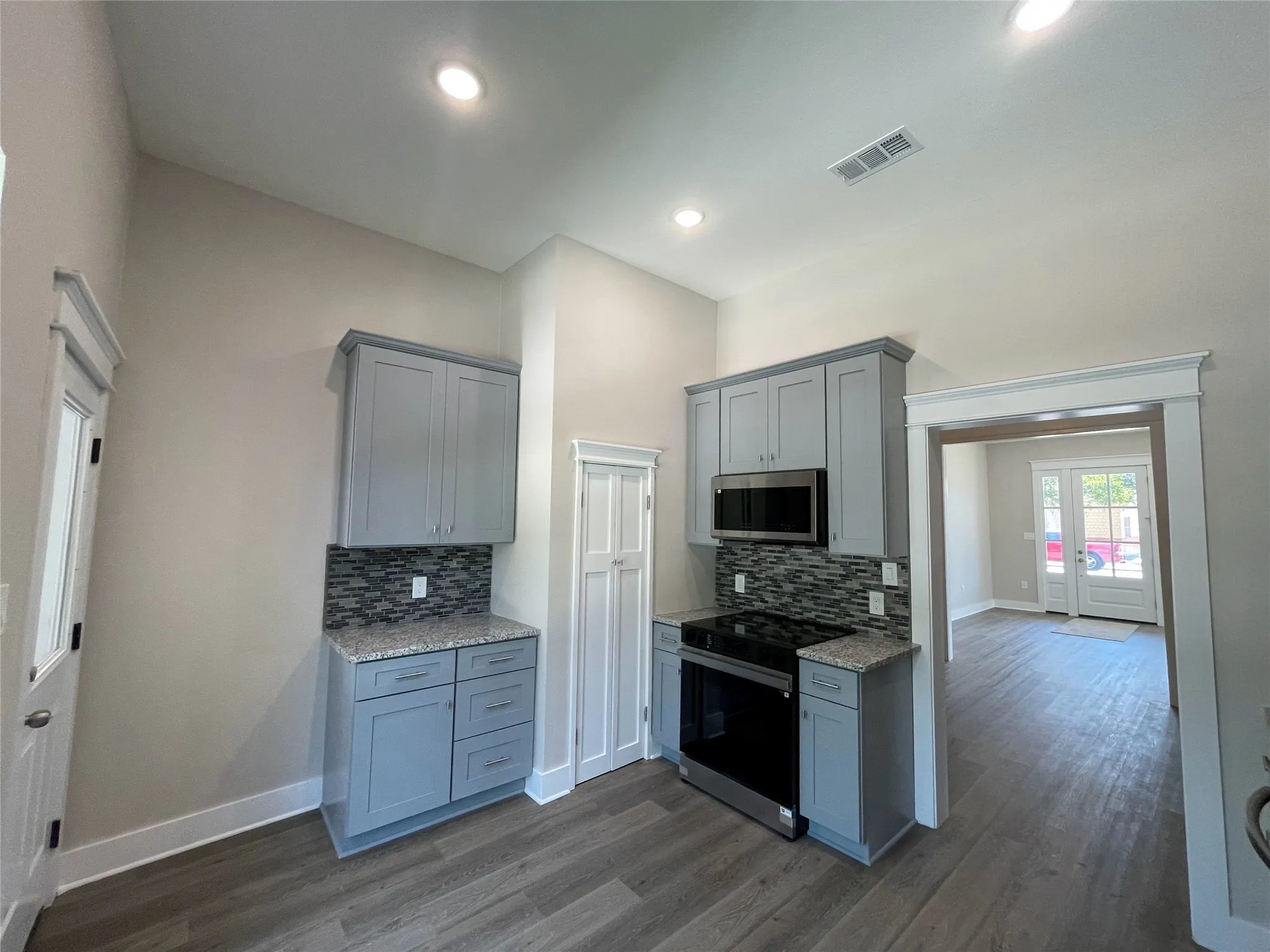 Kitchen featuring gray cabinets, stainless steel appliances, dark wood-type flooring, light stone countertops, and recessed lighting