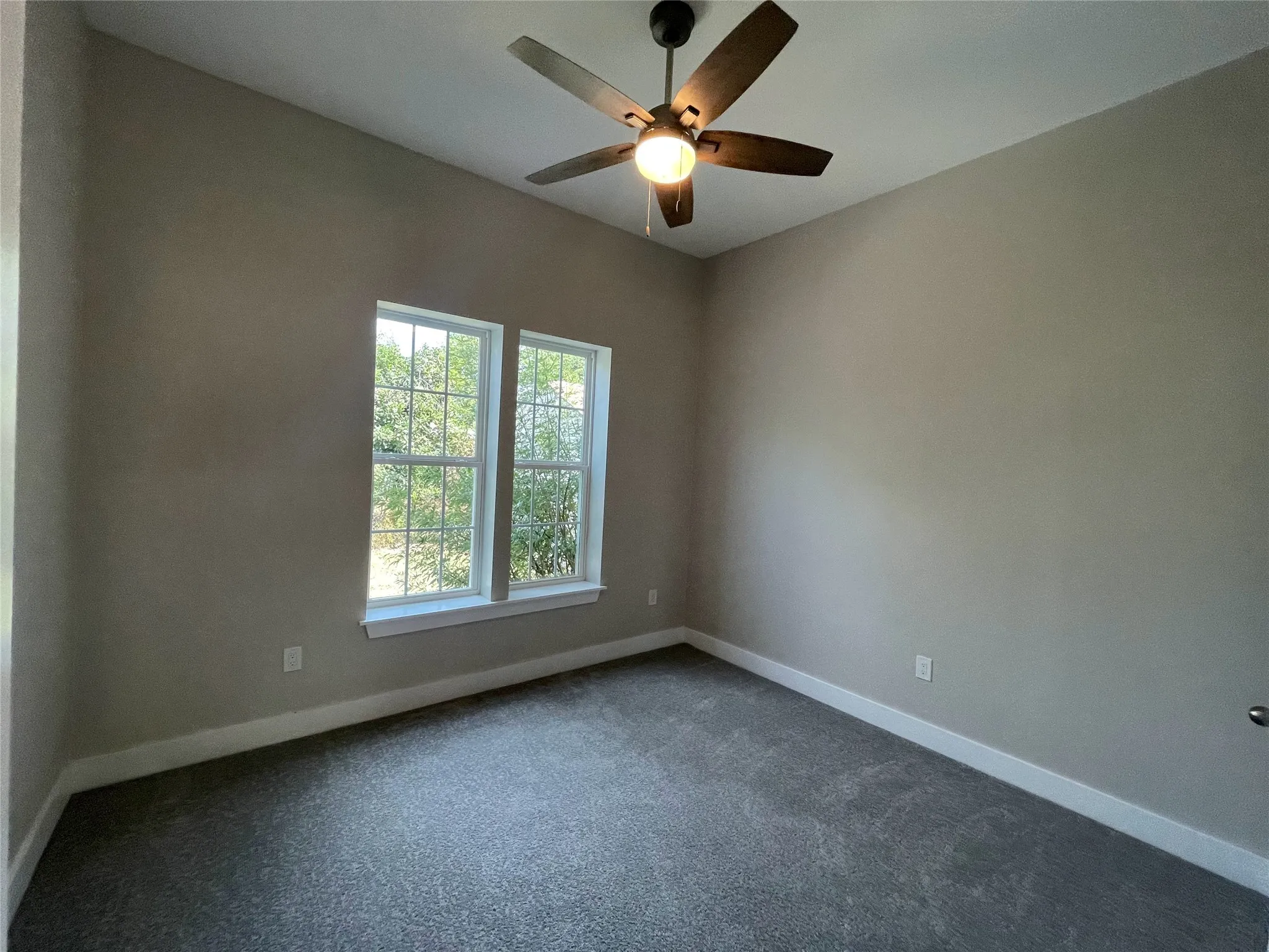 Carpeted spare room featuring baseboards and ceiling fan
