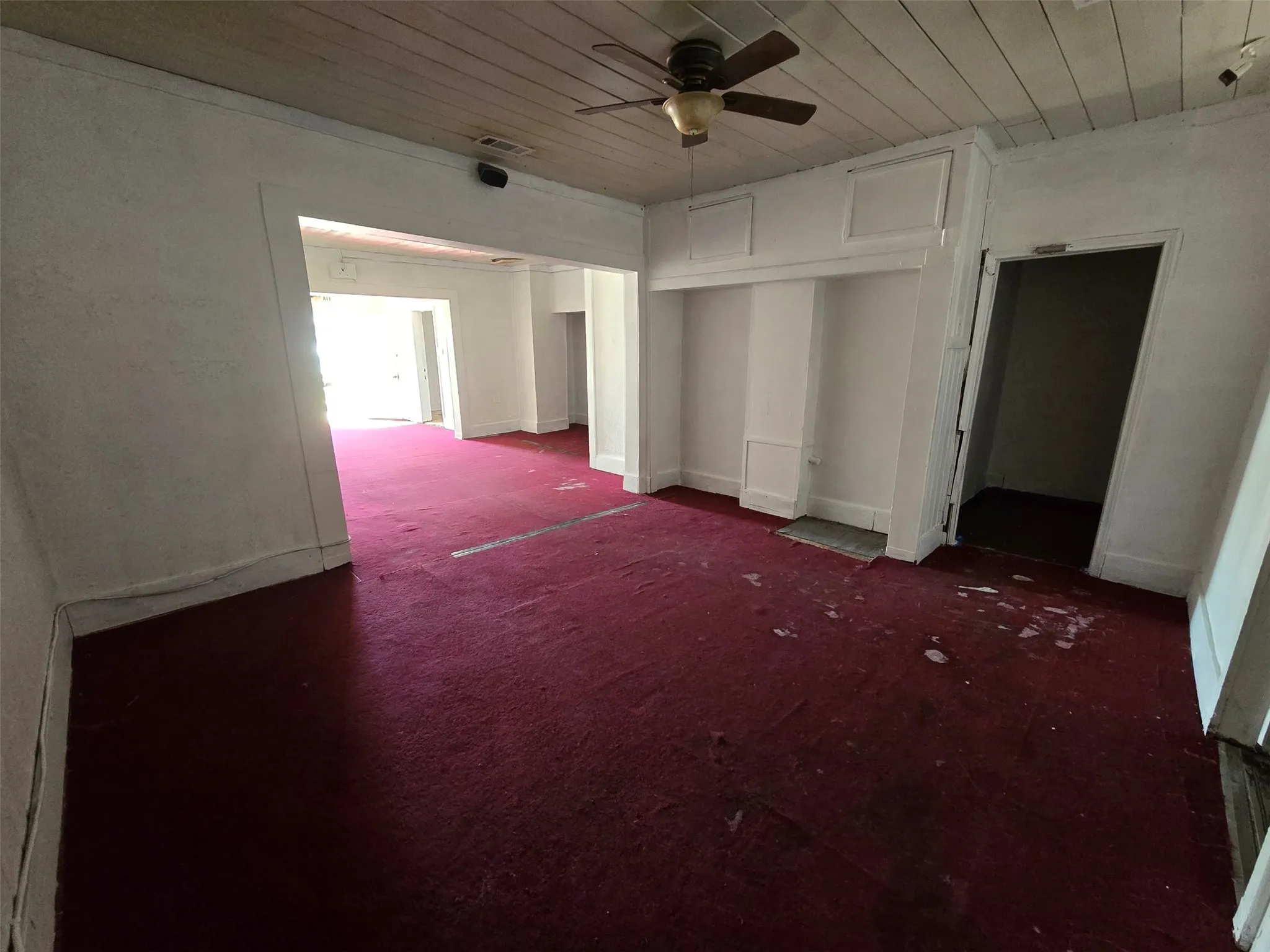 Unfurnished bedroom with dark colored carpet, wooden ceiling, a closet, and a ceiling fan