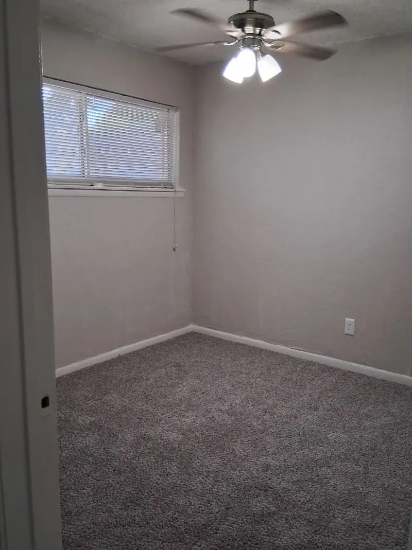 Carpeted empty room with baseboards and ceiling fan