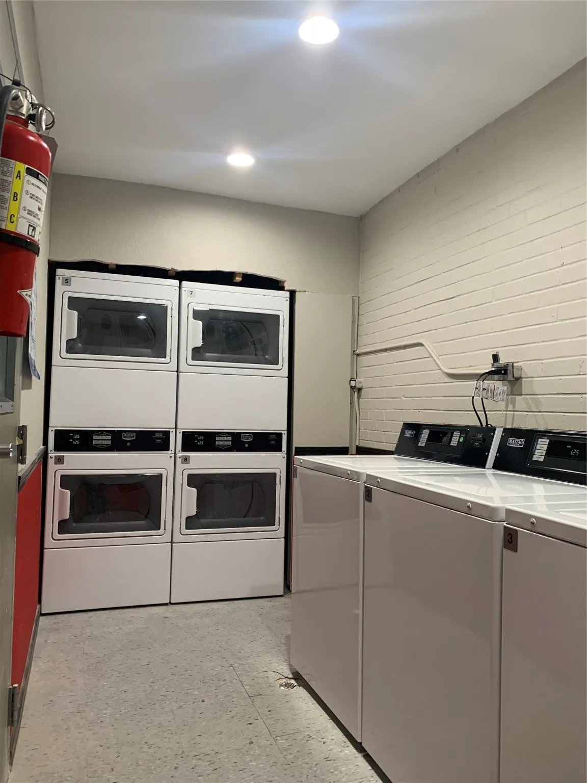 Community laundry with independent washer and dryer, stacked washer and clothes dryer, and recessed lighting