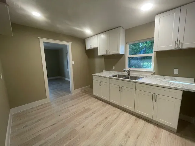 Kitchen featuring light wood finished floors, light stone countertops, white cabinets, and recessed lighting