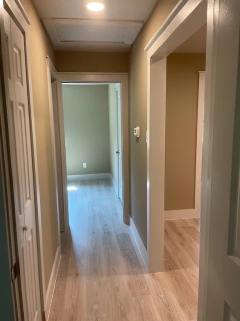 Hallway with light wood-type flooring and baseboards