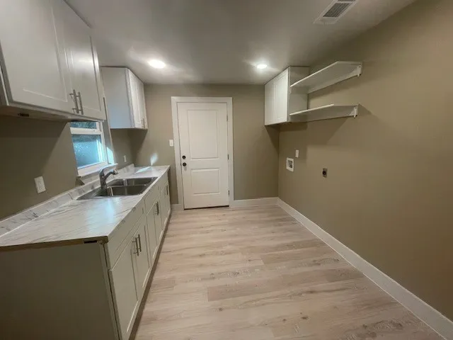 Laundry room with light wood-style flooring, hookup for a washing machine, cabinet space, and recessed lighting