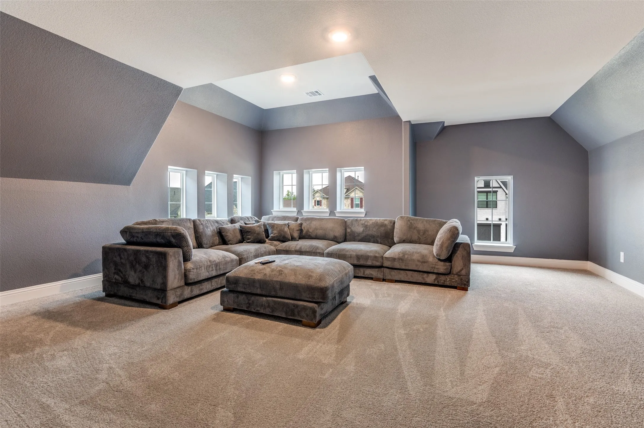 Carpeted living area with vaulted ceiling and baseboards