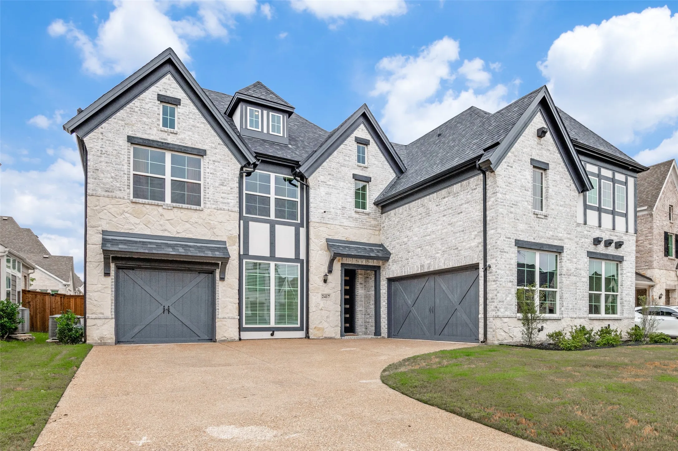 View of front of home with brick siding, a garage, a front yard, concrete driveway, and a high end roof