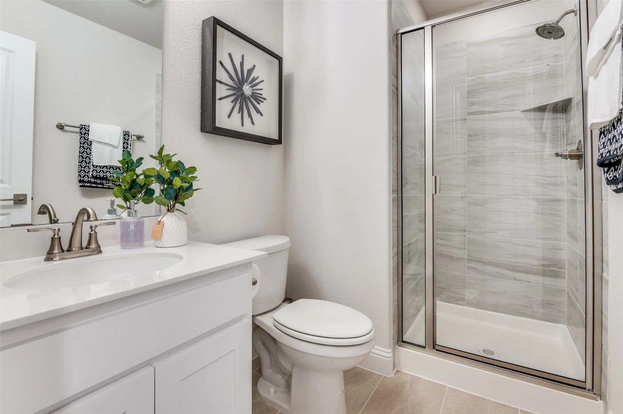 Full bathroom with a stall shower, vanity, and light tile patterned floors