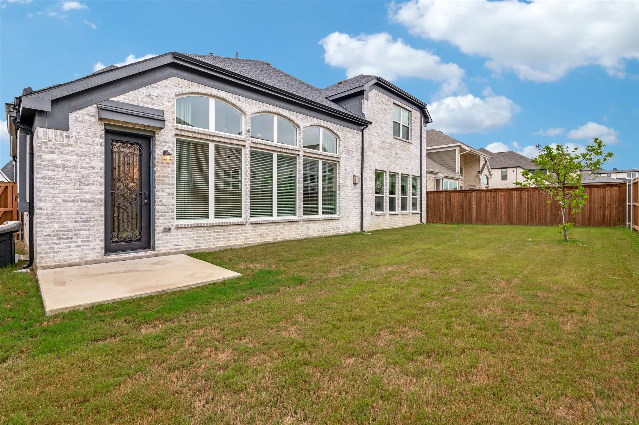Rear view of property with brick siding, a fenced backyard, and a patio area