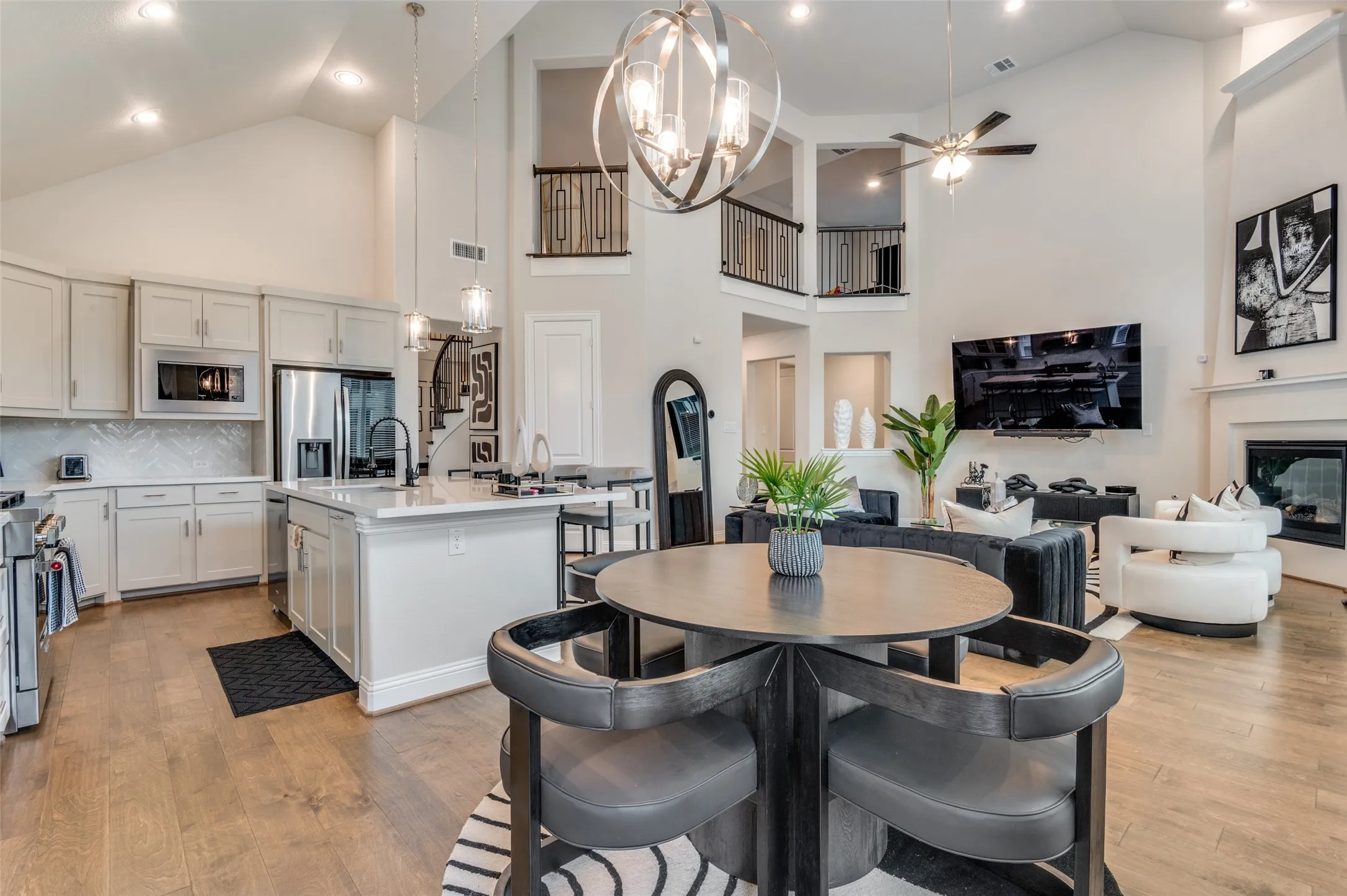 Dining space featuring a chandelier, light wood finished floors, a glass covered fireplace, high vaulted ceiling, and stairway