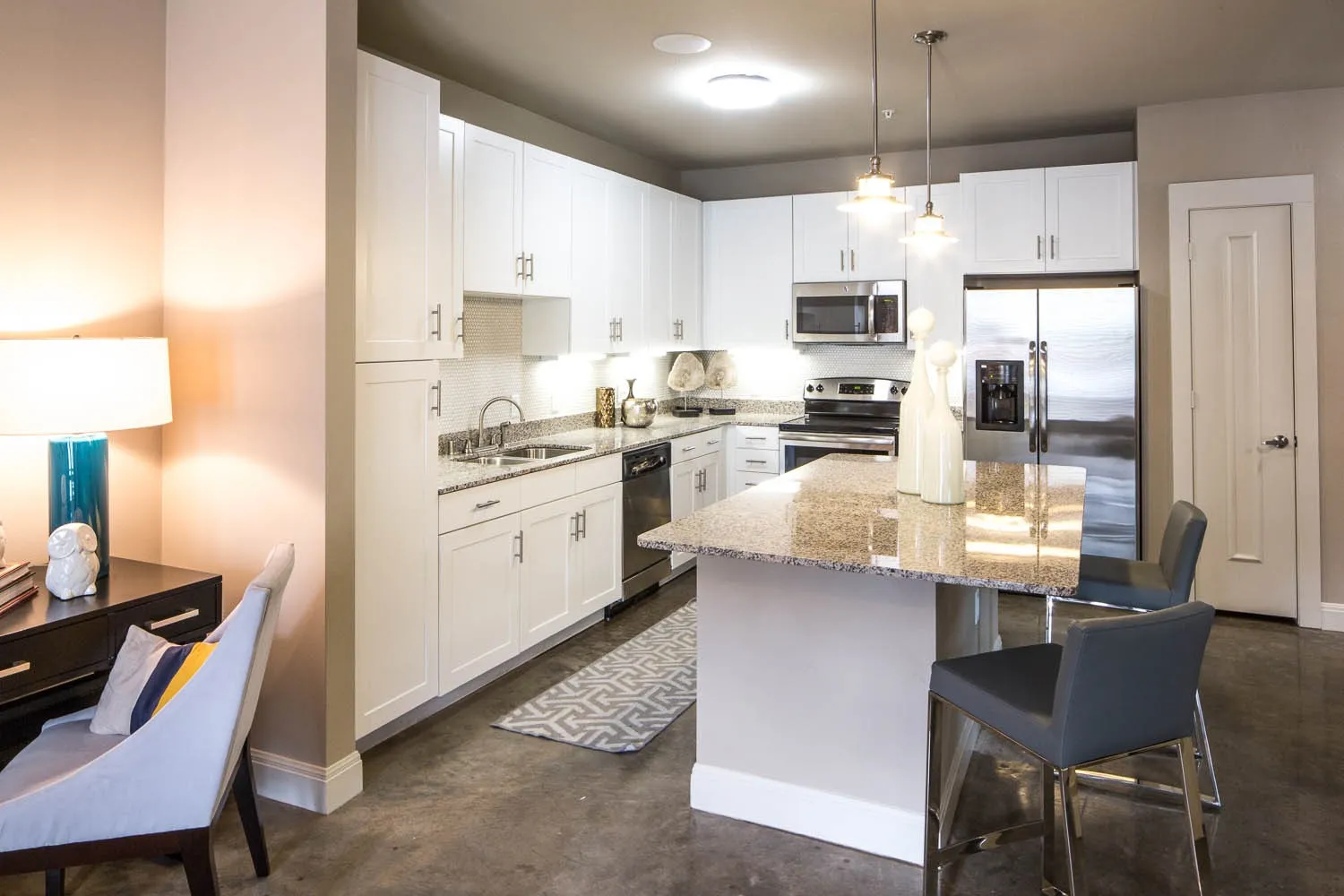 Kitchen with light stone counters, decorative light fixtures, stainless steel appliances, and white cabinets