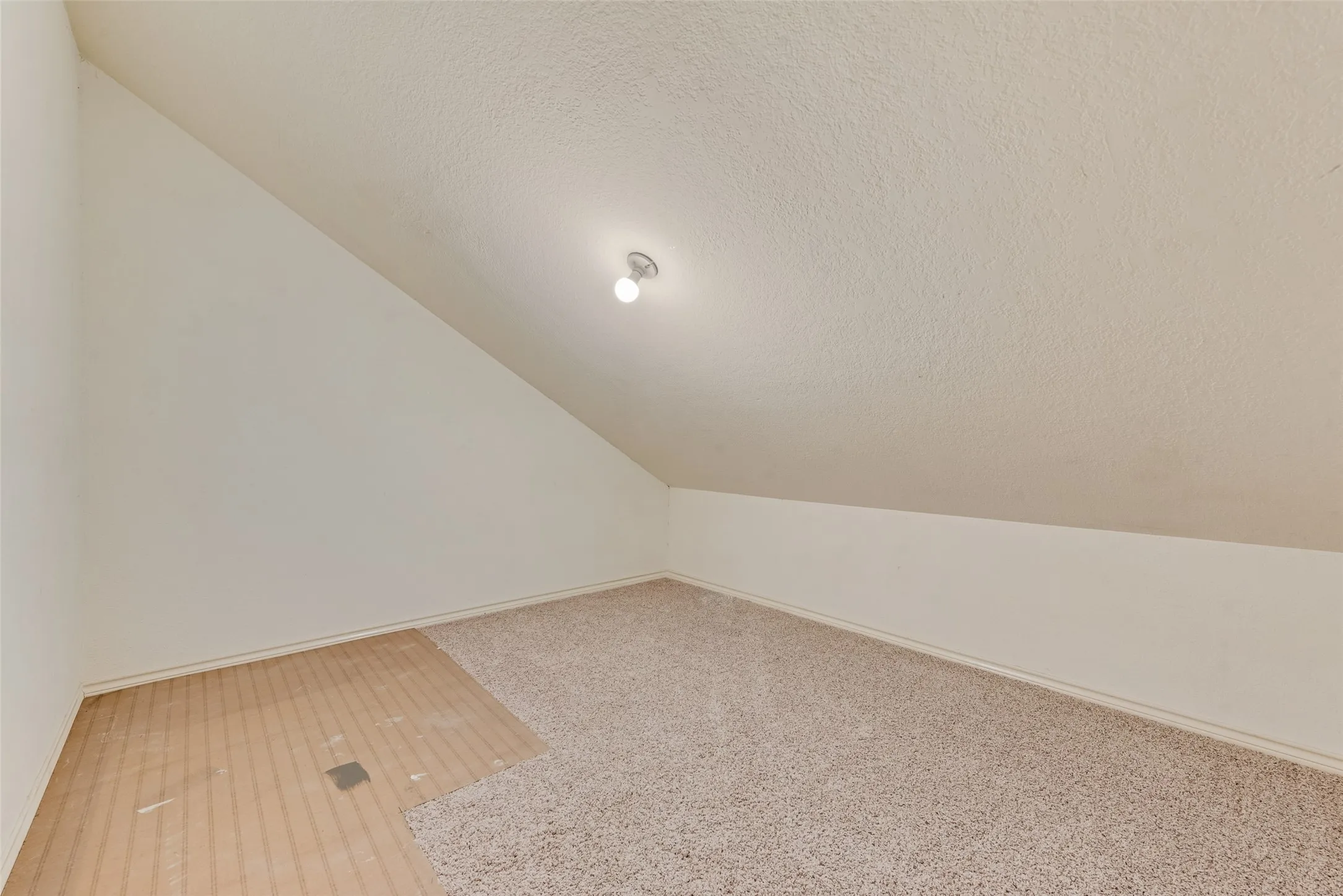 Bonus room with a textured ceiling and vaulted ceiling