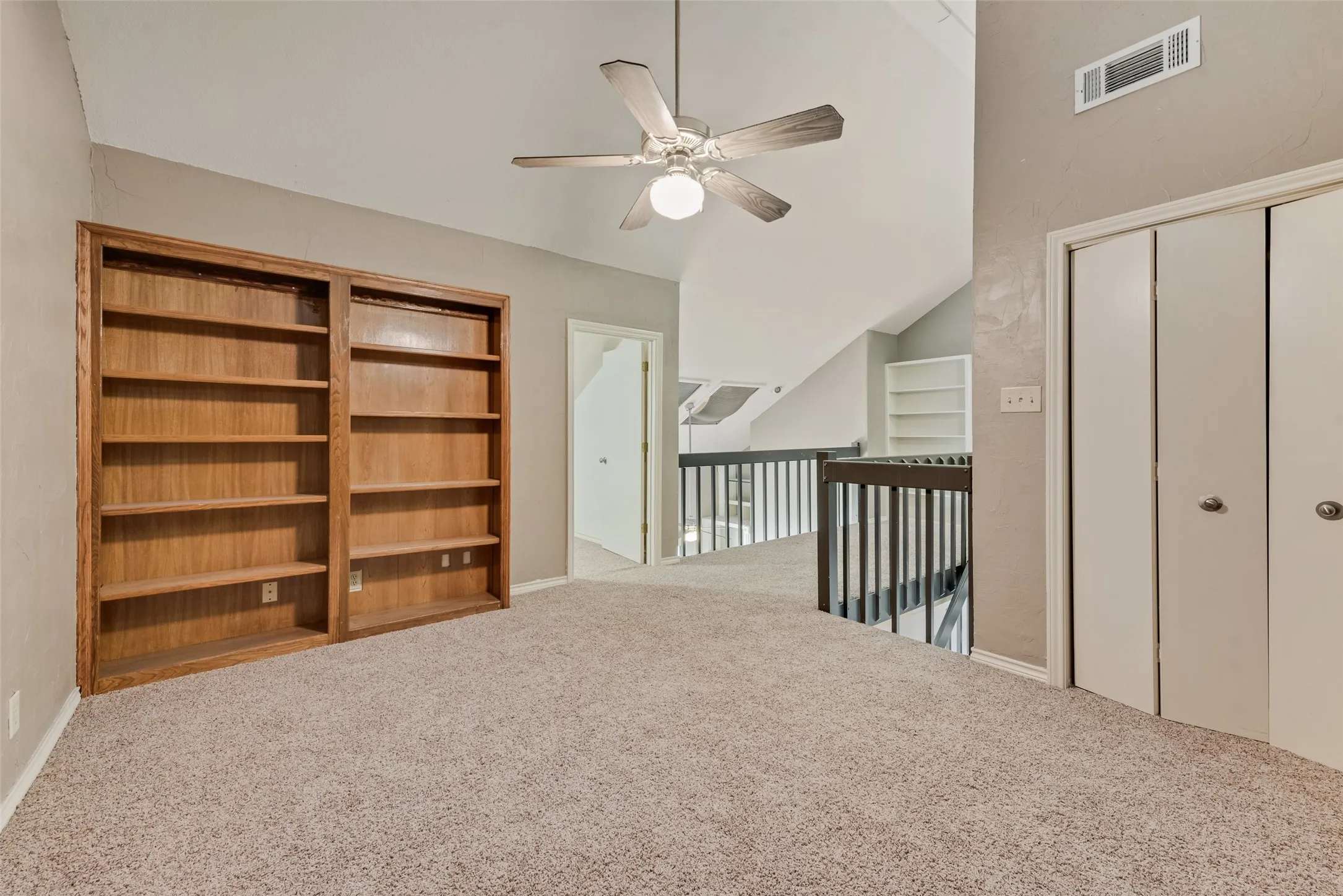 Corridor with carpet flooring, high vaulted ceiling, and built in shelves