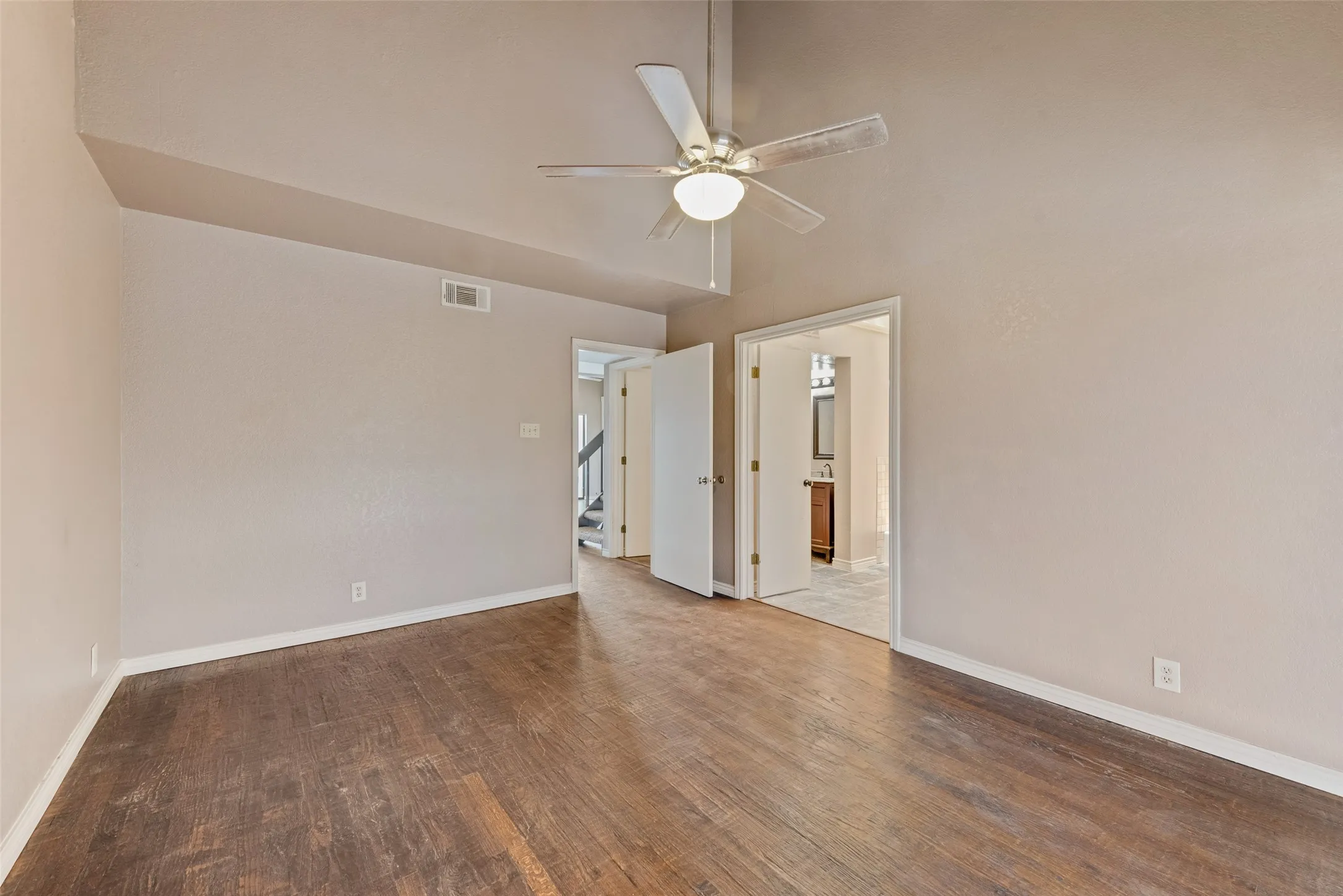 Spare room with dark wood-type flooring, a ceiling fan, and a towering ceiling