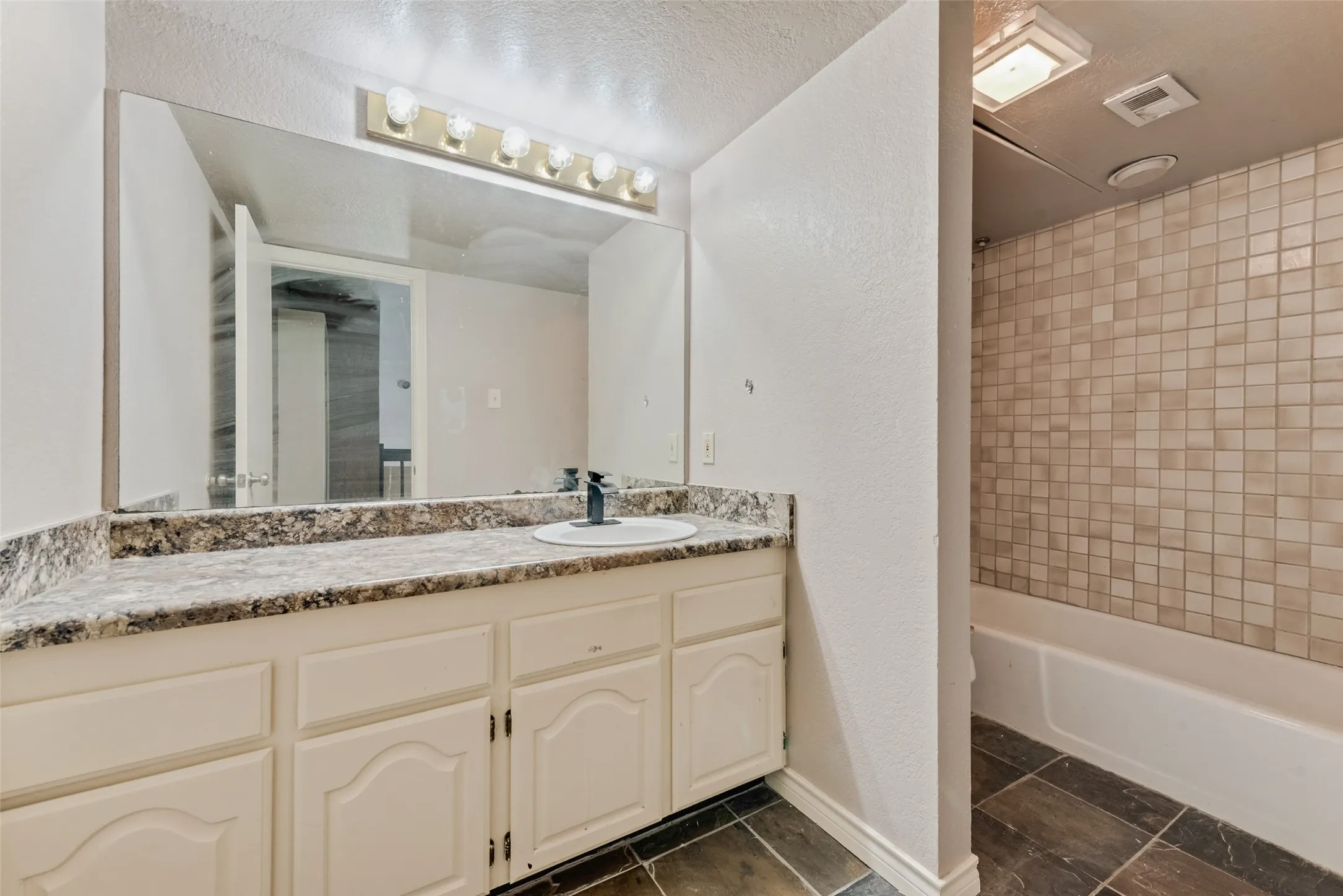 Full bath featuring shower / washtub combination, vanity, a textured wall, and a textured ceiling