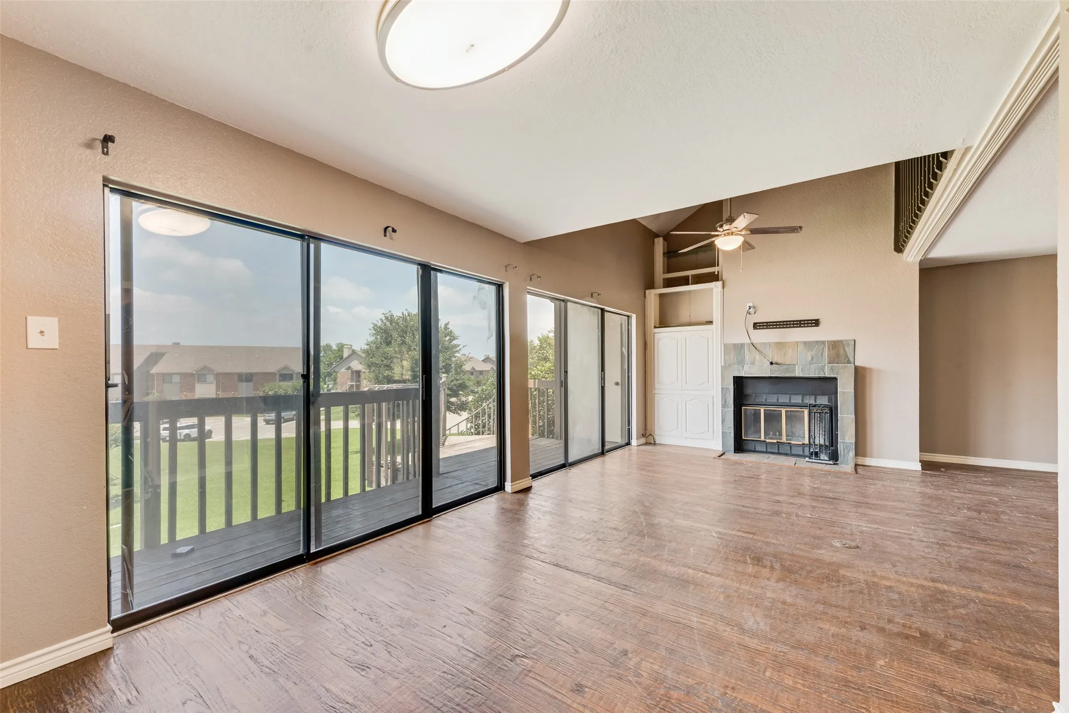 Unfurnished living room with wood finished floors, a fireplace, a ceiling fan, and vaulted ceiling
