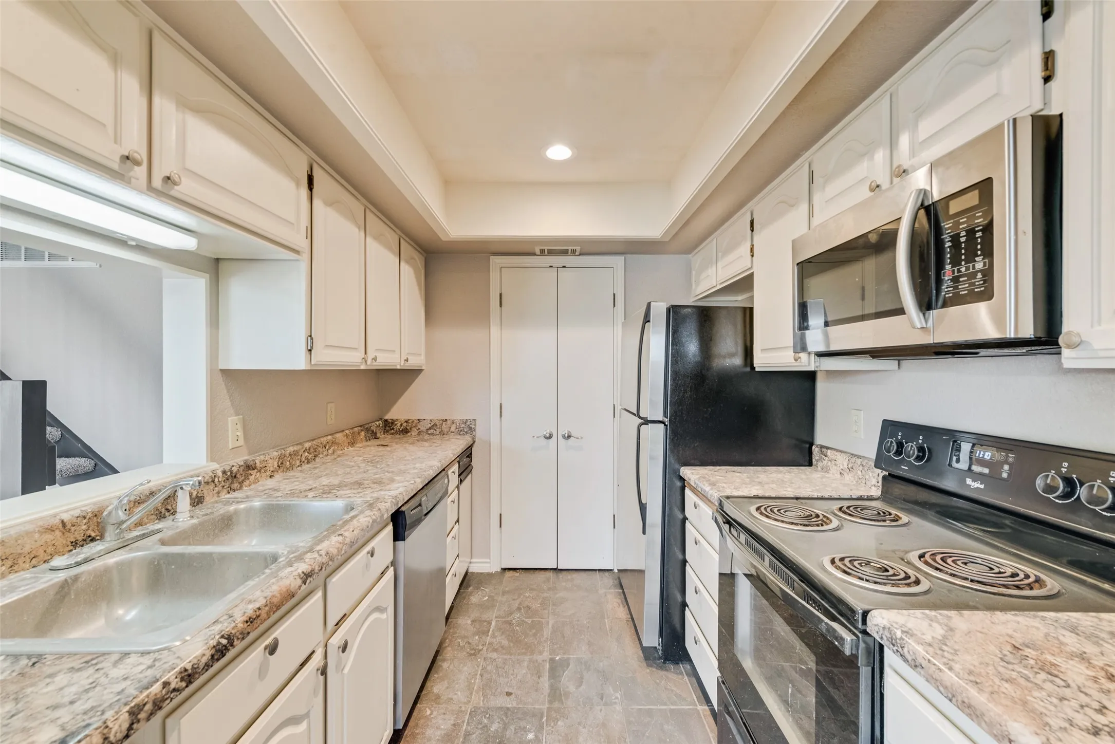 Kitchen featuring appliances with stainless steel finishes, light countertops, white cabinets, a tray ceiling, and recessed lighting