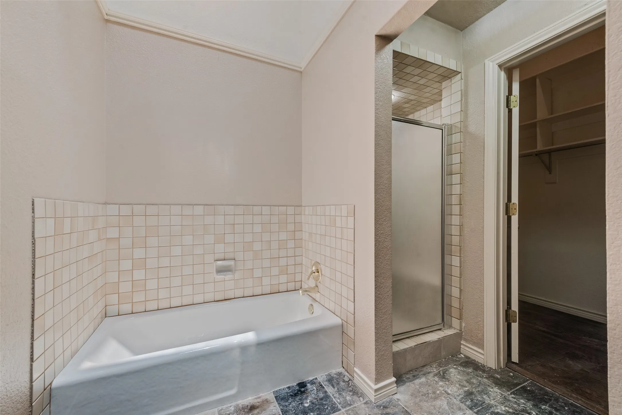 Full bath featuring a shower stall, a garden tub, and a walk in closet