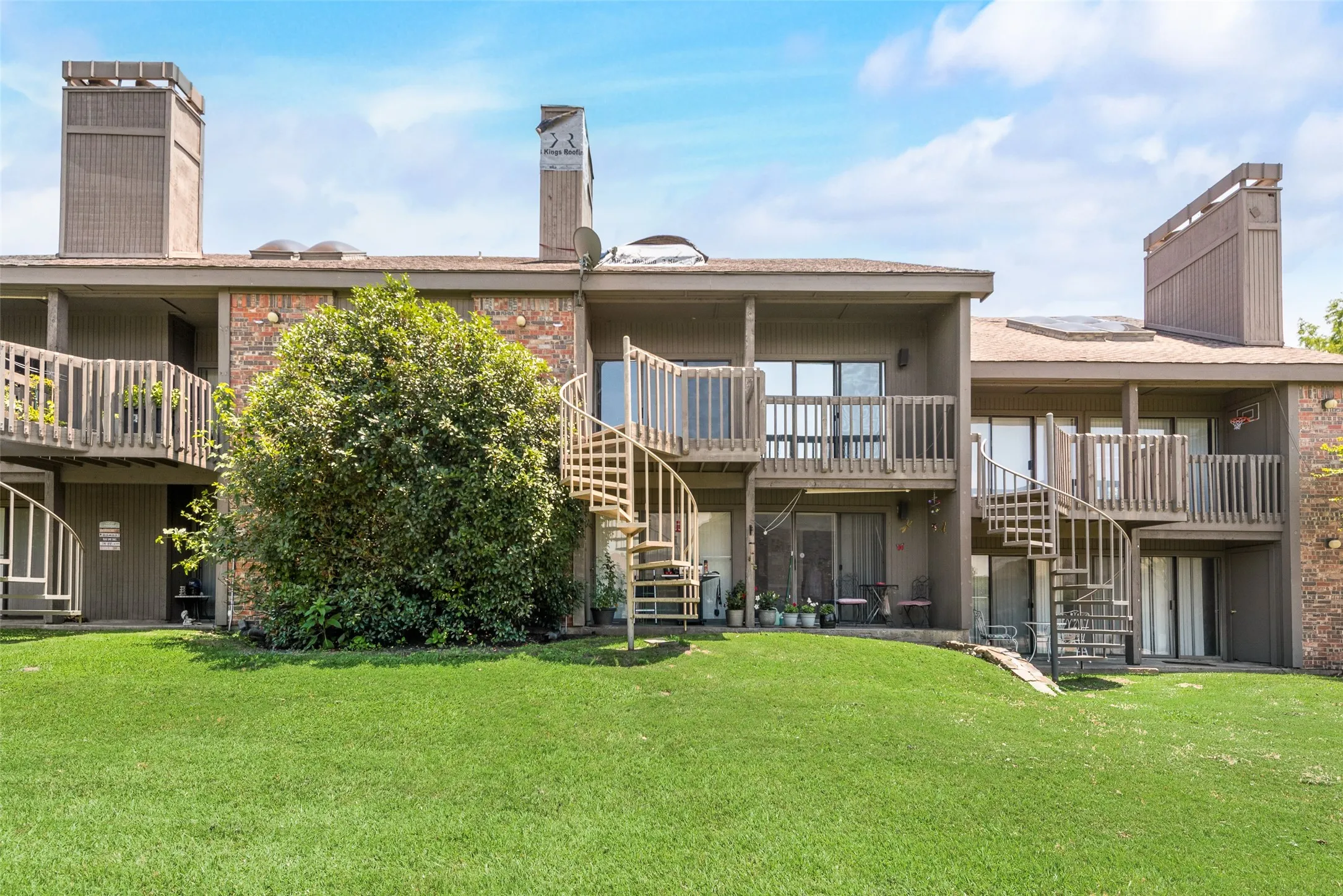 Back of house featuring stairway, a chimney, a lawn, a patio area, and brick siding
