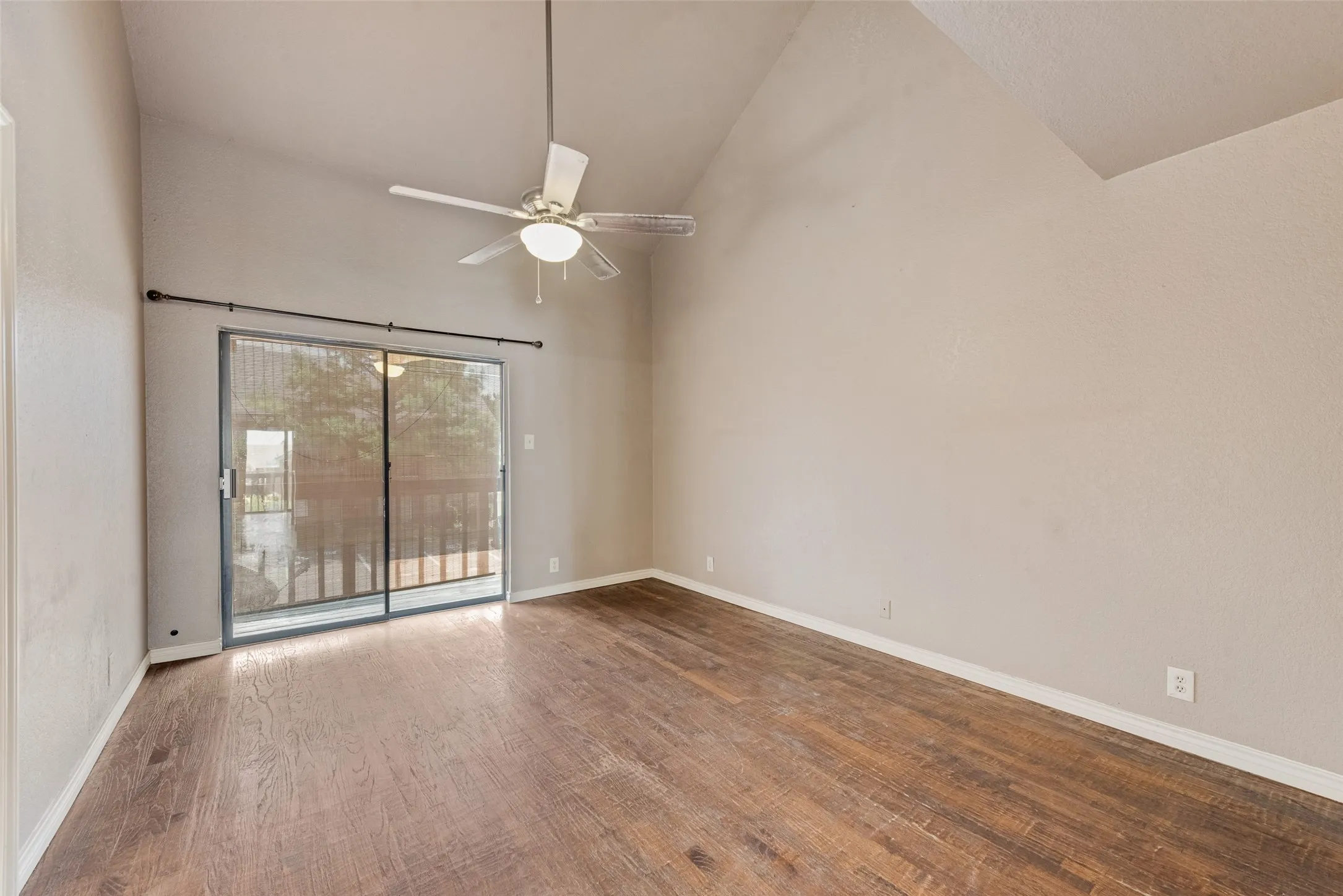 Empty room with high vaulted ceiling, wood finished floors, and ceiling fan